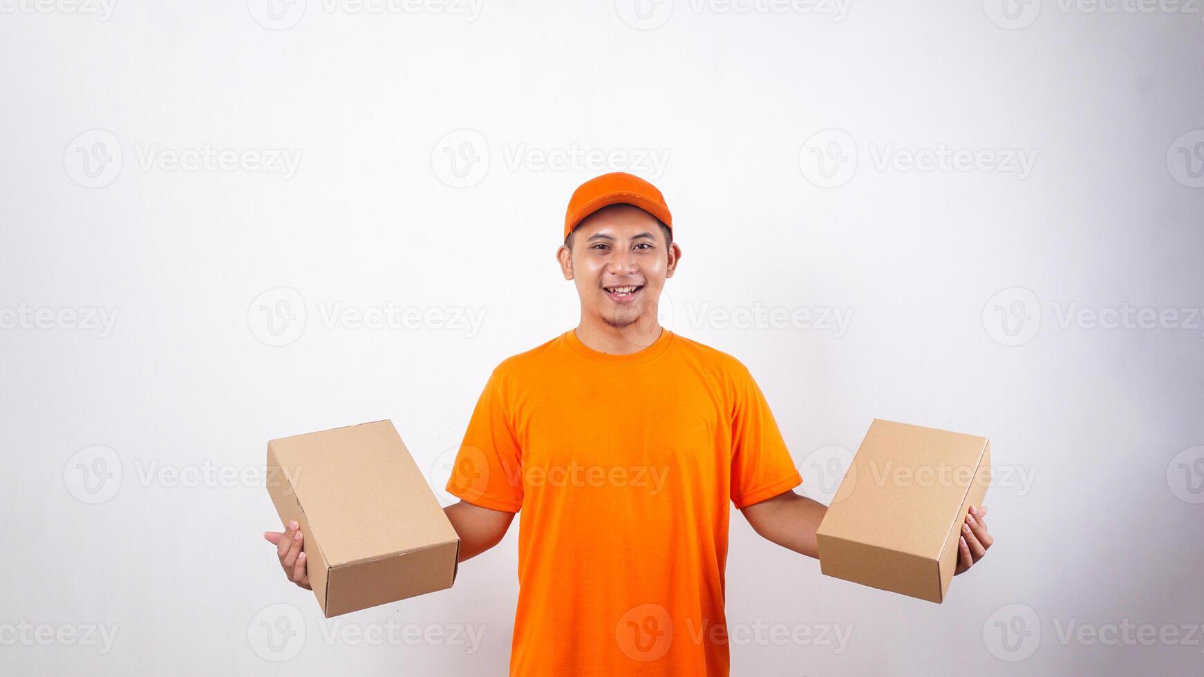 Asian deliveryman in orange t-shirt uniform with package boxes parcel in both hands isolated on white background photo