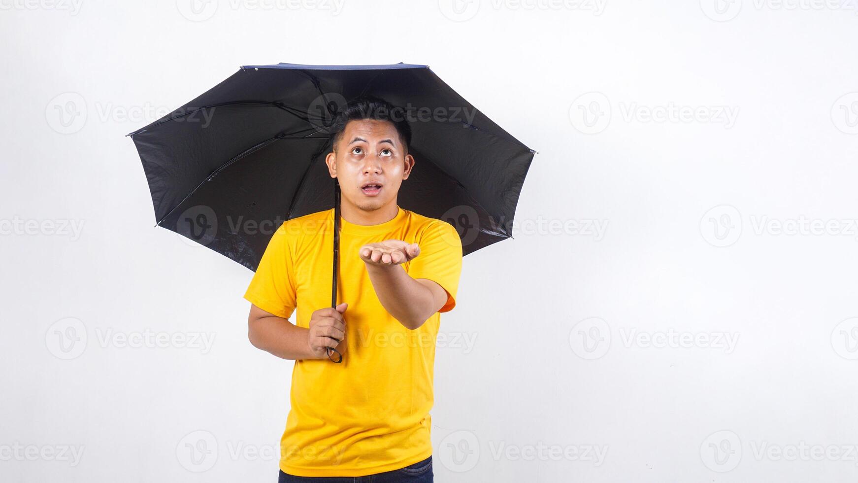 Asian man holding umbrella and checking if rain stopped isolated on white background photo