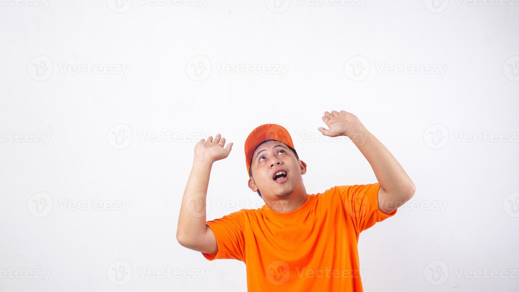 Asian deliveryman in orange t-shirt uniform poses as if he is hit by something from above isolated on white background photo