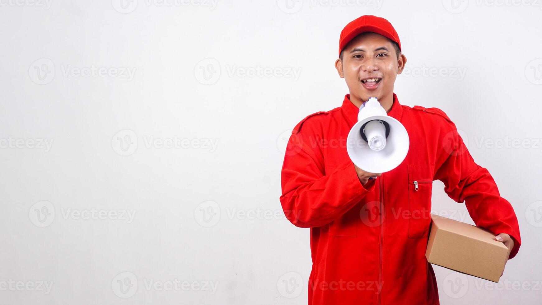 Asian Delivery man in red uniform carrying a package box parcel while talk using megaphone isolated on white background photo