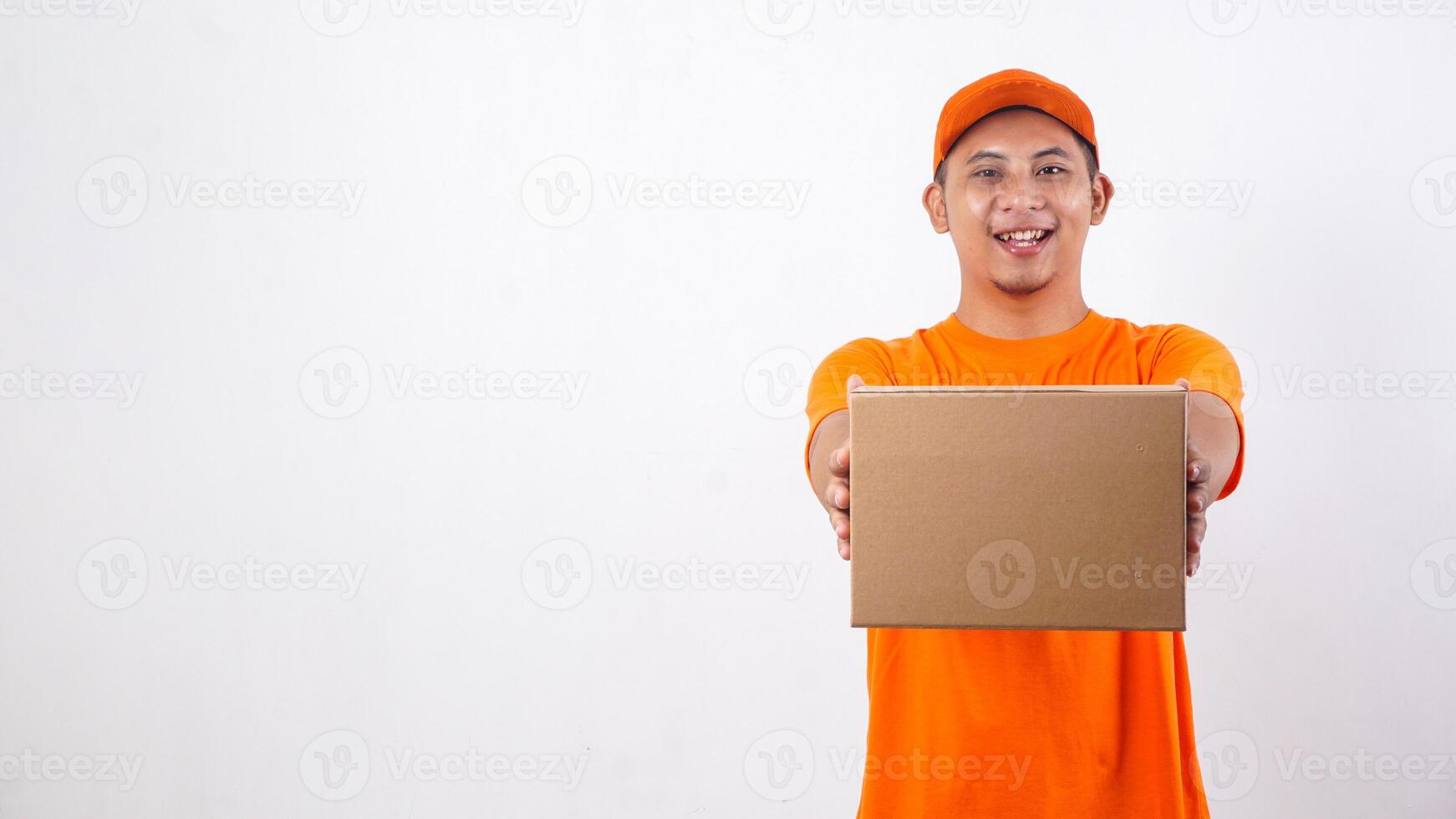 Smiling Asian deliveryman in orange t-shirt uniform giving a package box parcel to customer isolated on white background photo