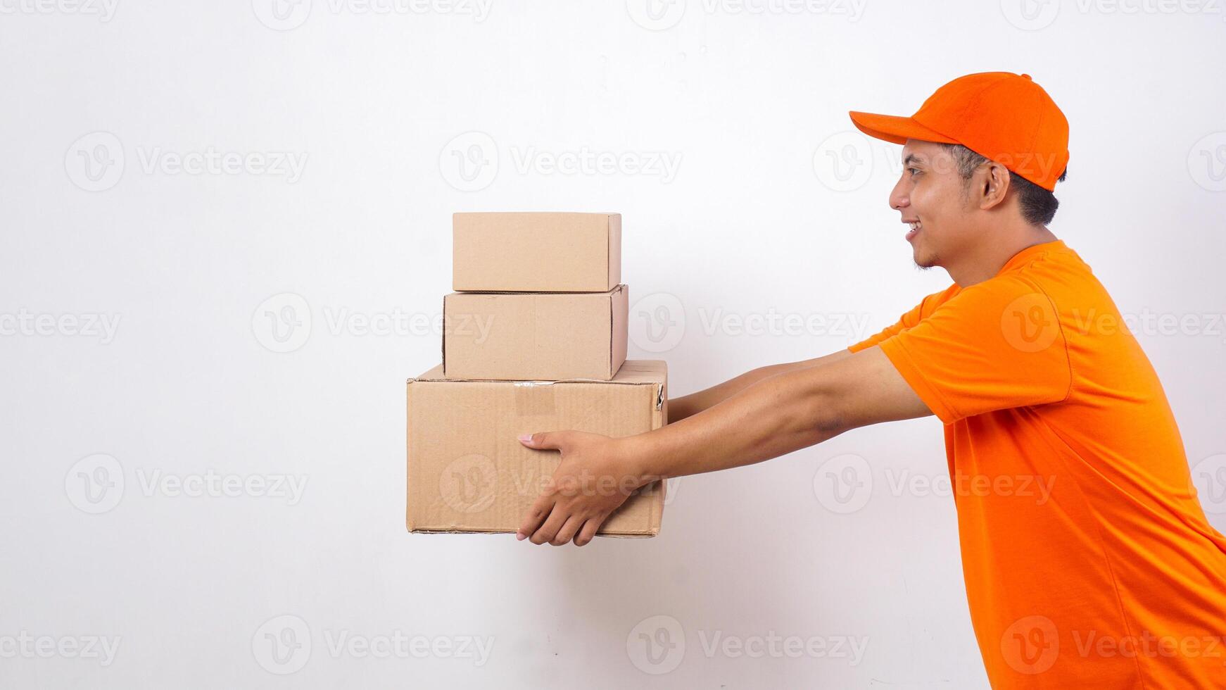 Side view of Asian deliveryman in orange t-shirt uniform delivering stack of package boxes parcel to customer isolated on white background photo
