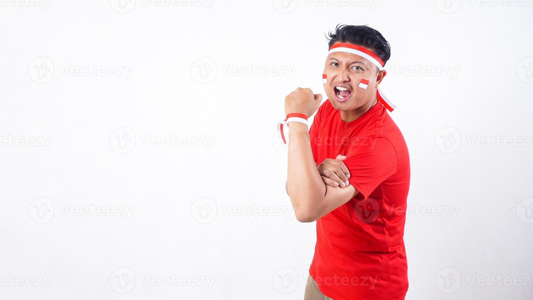 Indonesian man excitedly celebrate Indonesia independence day on 17 August with arms raised isolated on white background photo