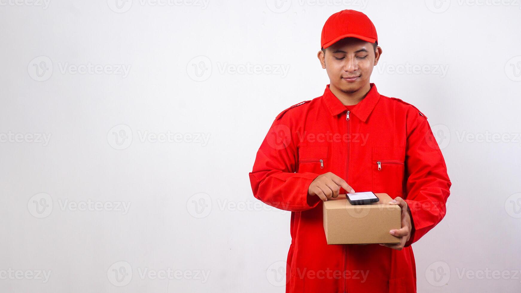 Asian Delivery man in red uniform holding package box parcel with phone on top isolated on white background photo