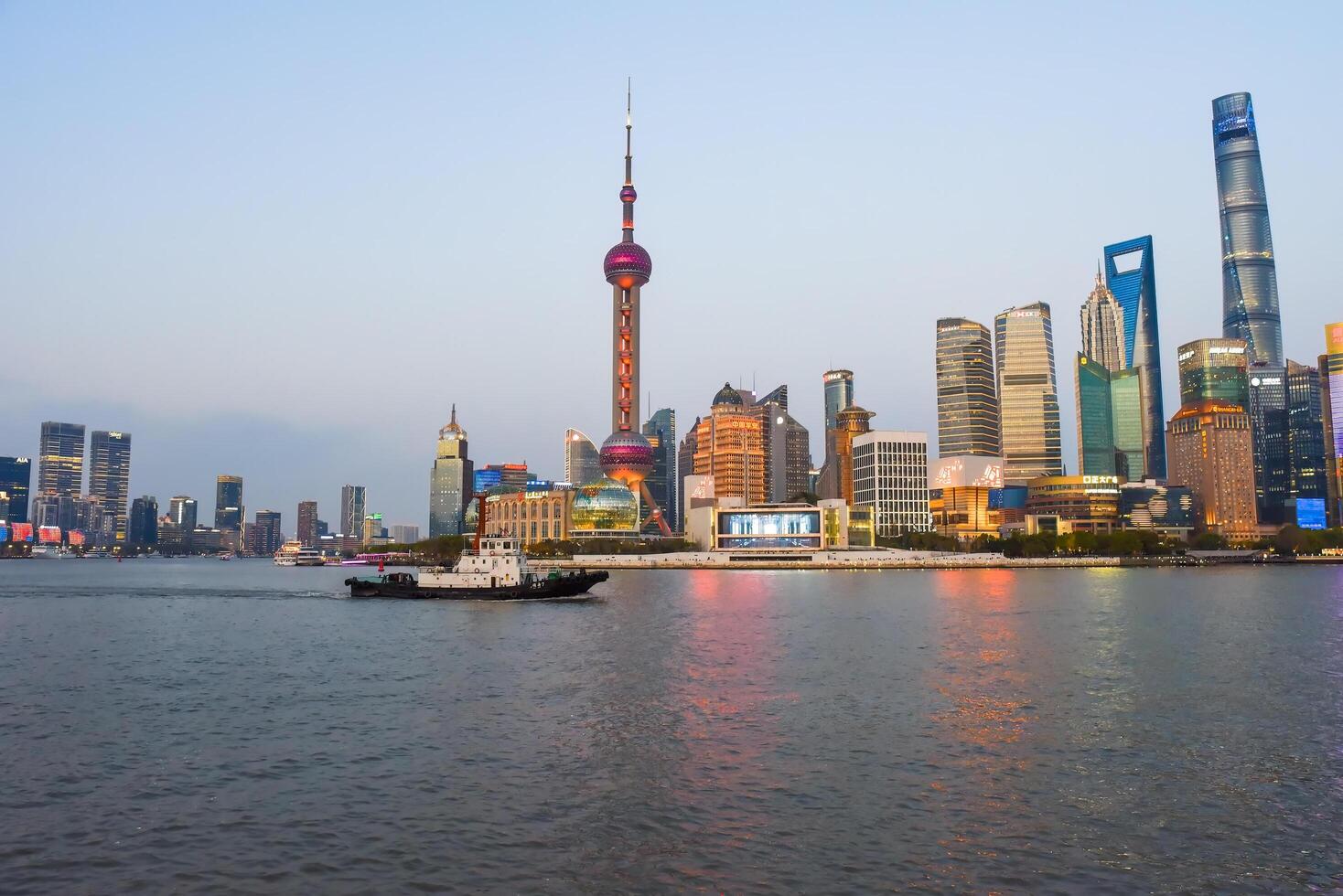 Shanghai, China - 1 April 2025 Tourist boat passes along the Bund waterfront in front of Pudong skyline featuring Oriental Pearl Tower and Shanghai Tower photo