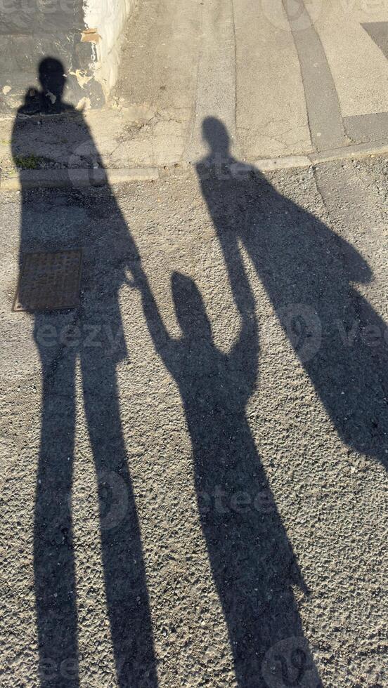 Shadows of Three Figures on Asphalt Surface photo