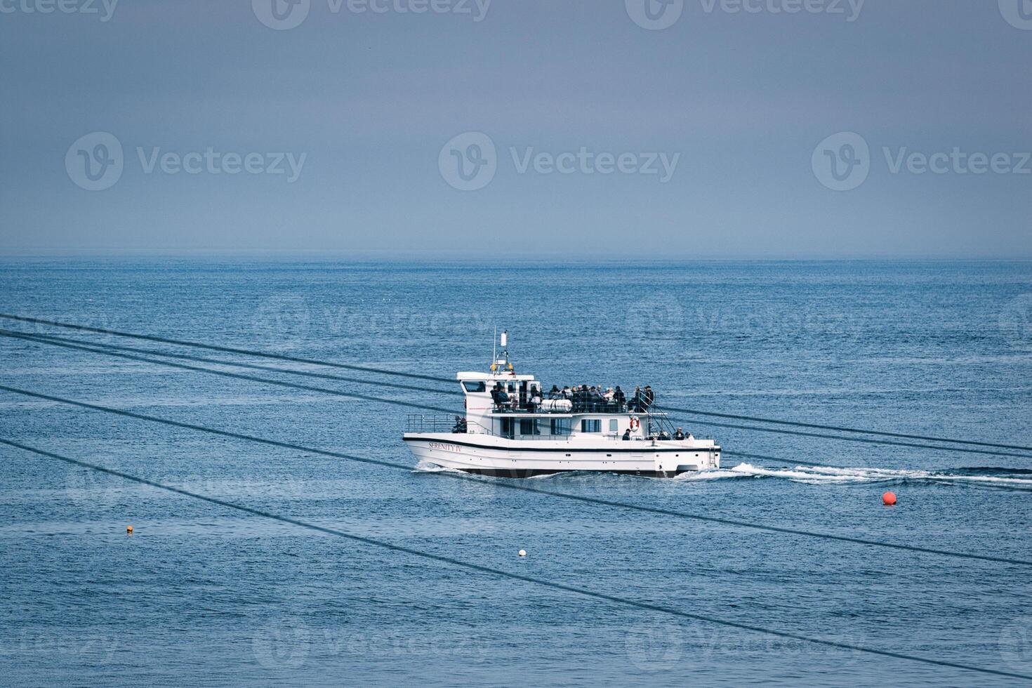 Passenger Boat on Ocean with Overhead Wires at Seahouses Harbour, UK photo