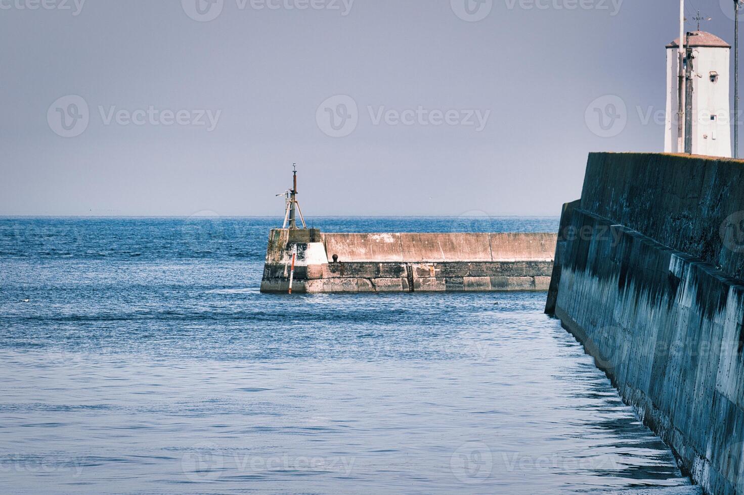 Concrete Pier Walls and Lighthouse in a Seascape at Seahouses Harbour, UK photo