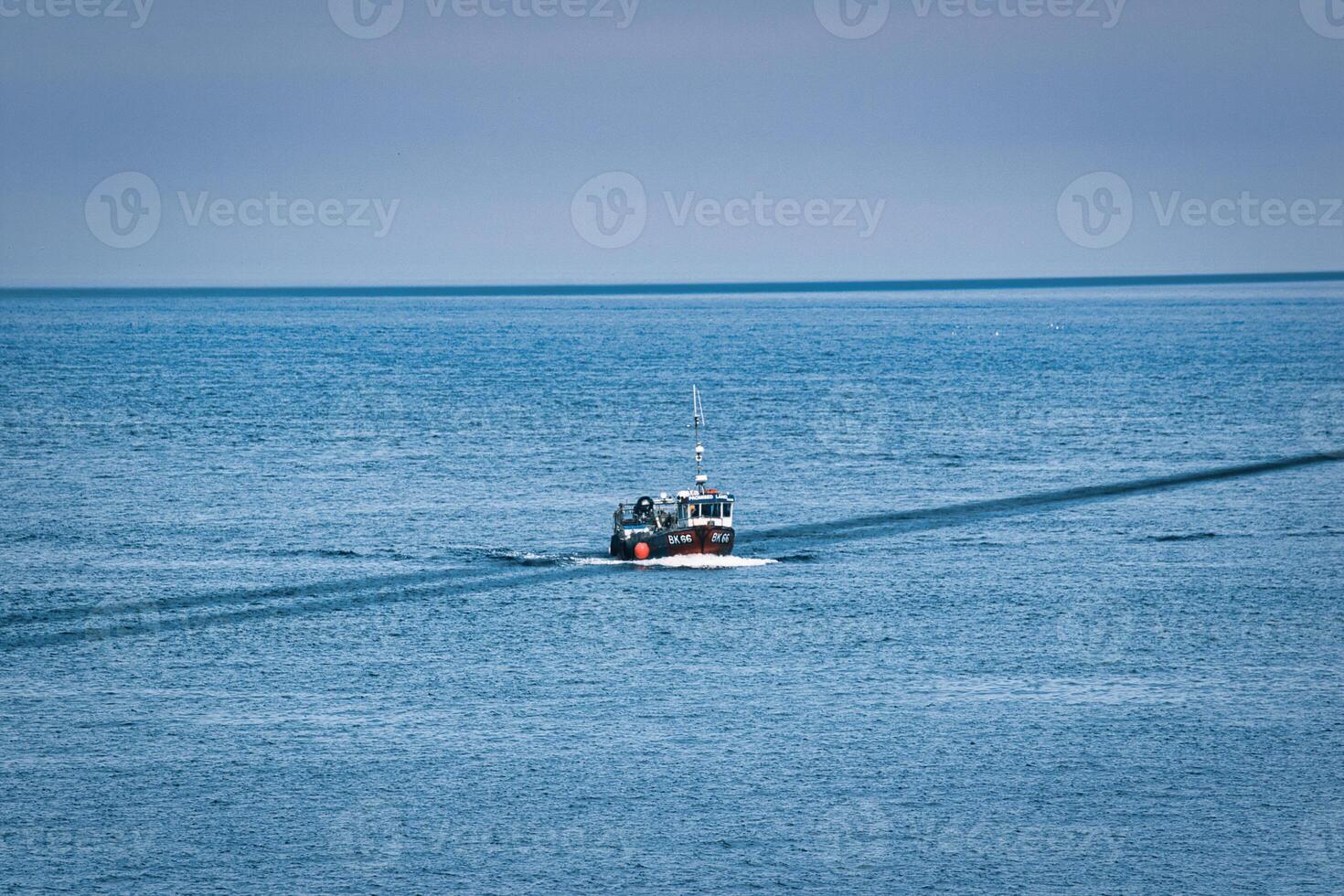 Fishing Boat in Ocean with Wake at Seahouses Harbour, UK photo