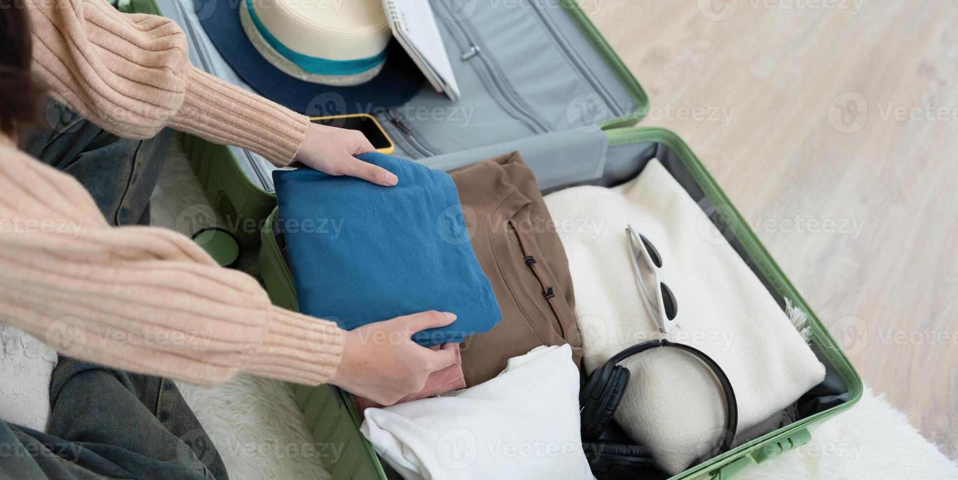 female are checking the detail and quantity of items used during the trip by tablet. Young women are prepare clothes and personal belongings. Pack your luggage before travel. photo