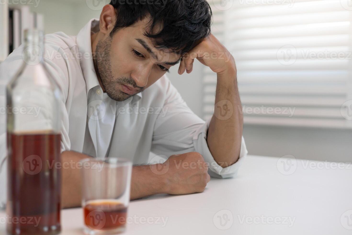 Depressed young Asian man addicted feeling bad drinking whiskey alone at home, stressed frustrated lonely drinking alcohol suffers from problematic liquor, alcoholism, life and family problem photo