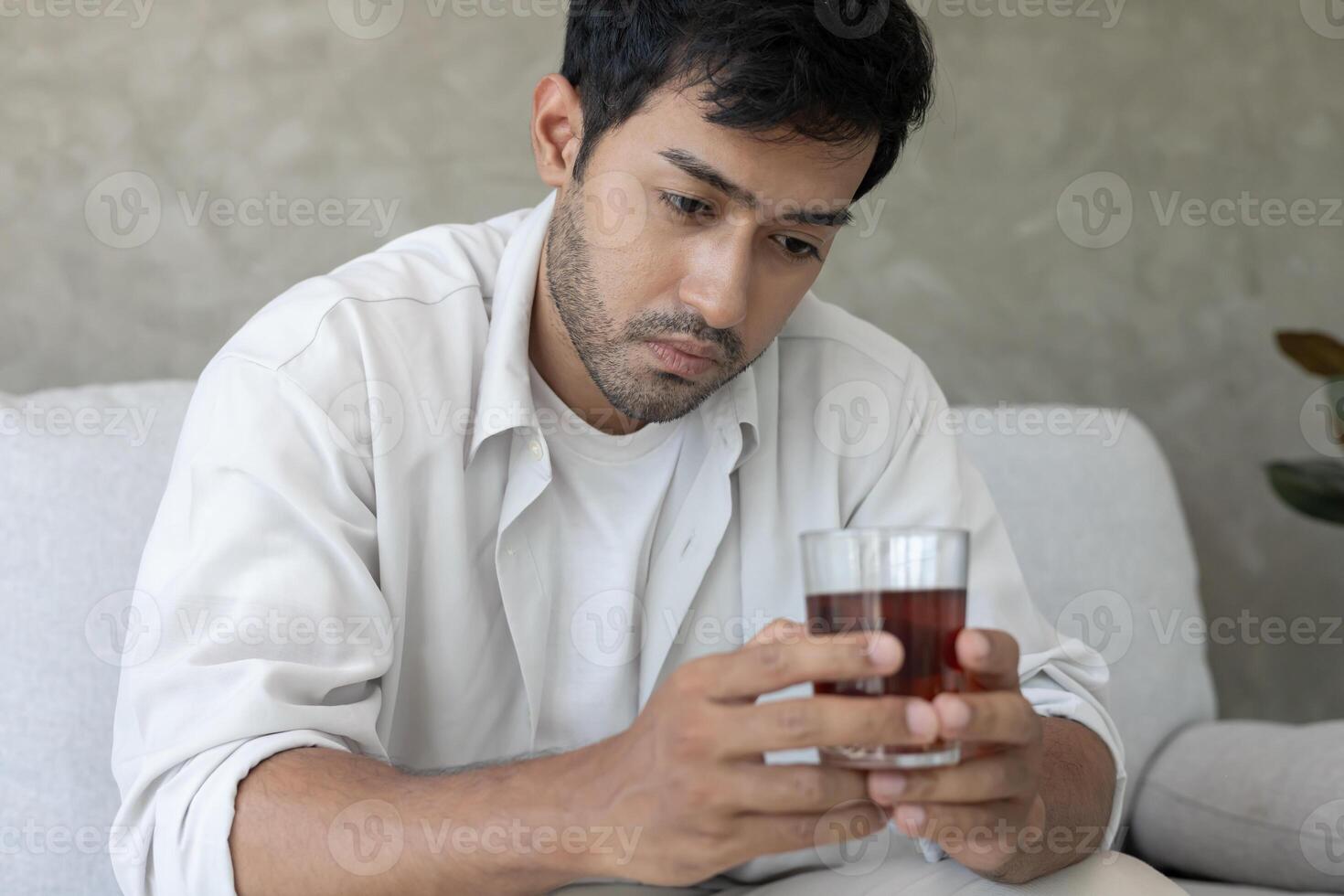 Depressed young man addicted feeling bad drinking whiskey alone at home, stressed frustrated lonely drinking alcohol suffers from problematic liquor, alcoholism, life and family problem photo