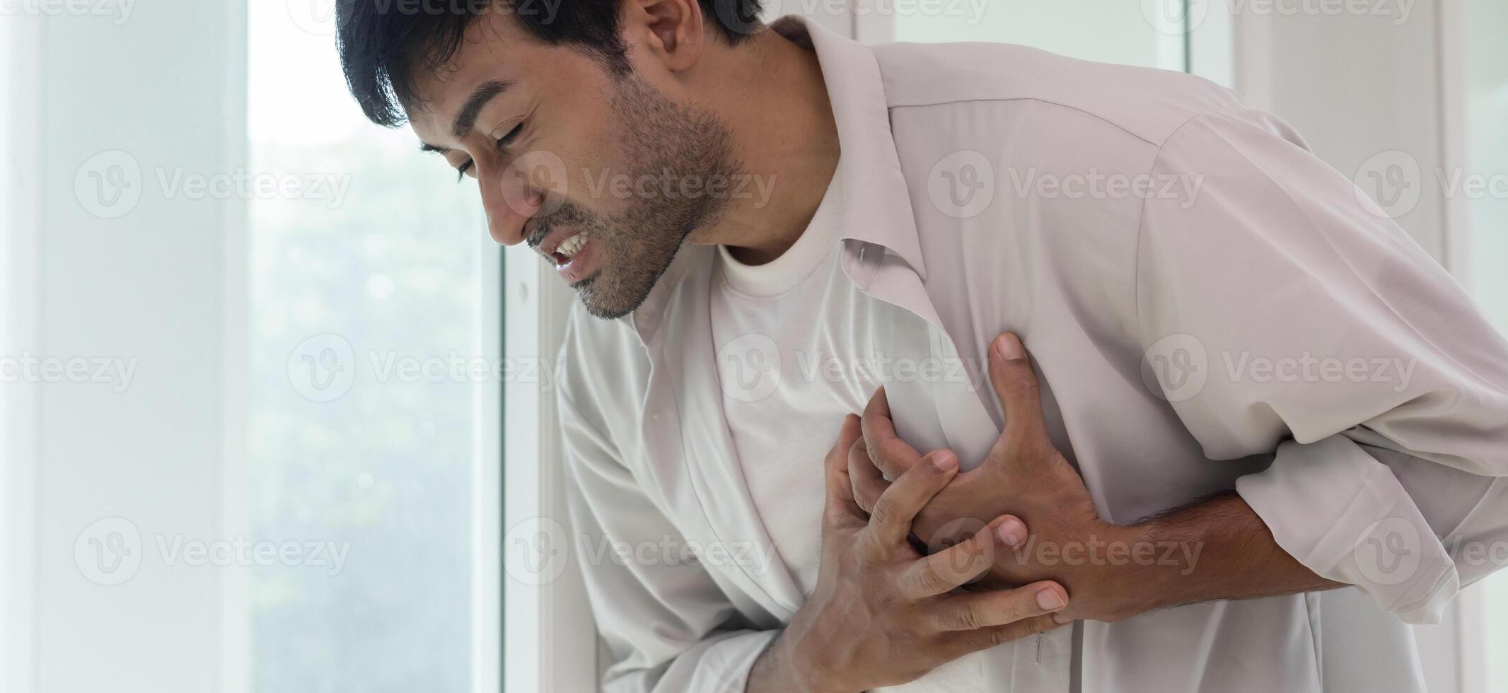 hand hold chest with heart attack symptoms. asian man have chest pain caused by heart disease, leak, dilatation, enlarged coronary heart, press on the chest with a painful expression photo