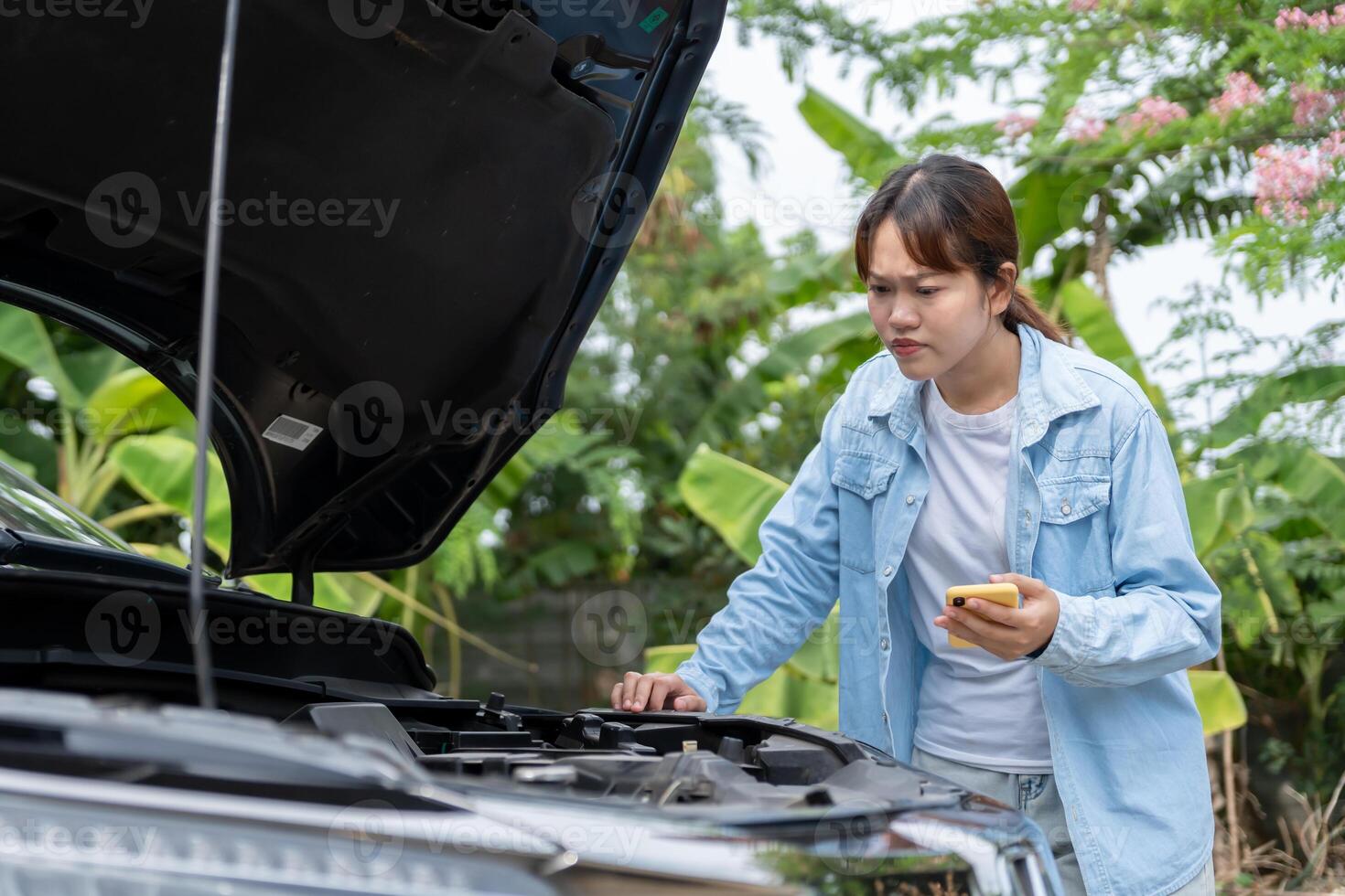 Woman uses mobile phone check insurance premiums through application due to car accident . Find garage to get car fixed during country tour, waiting for help photo