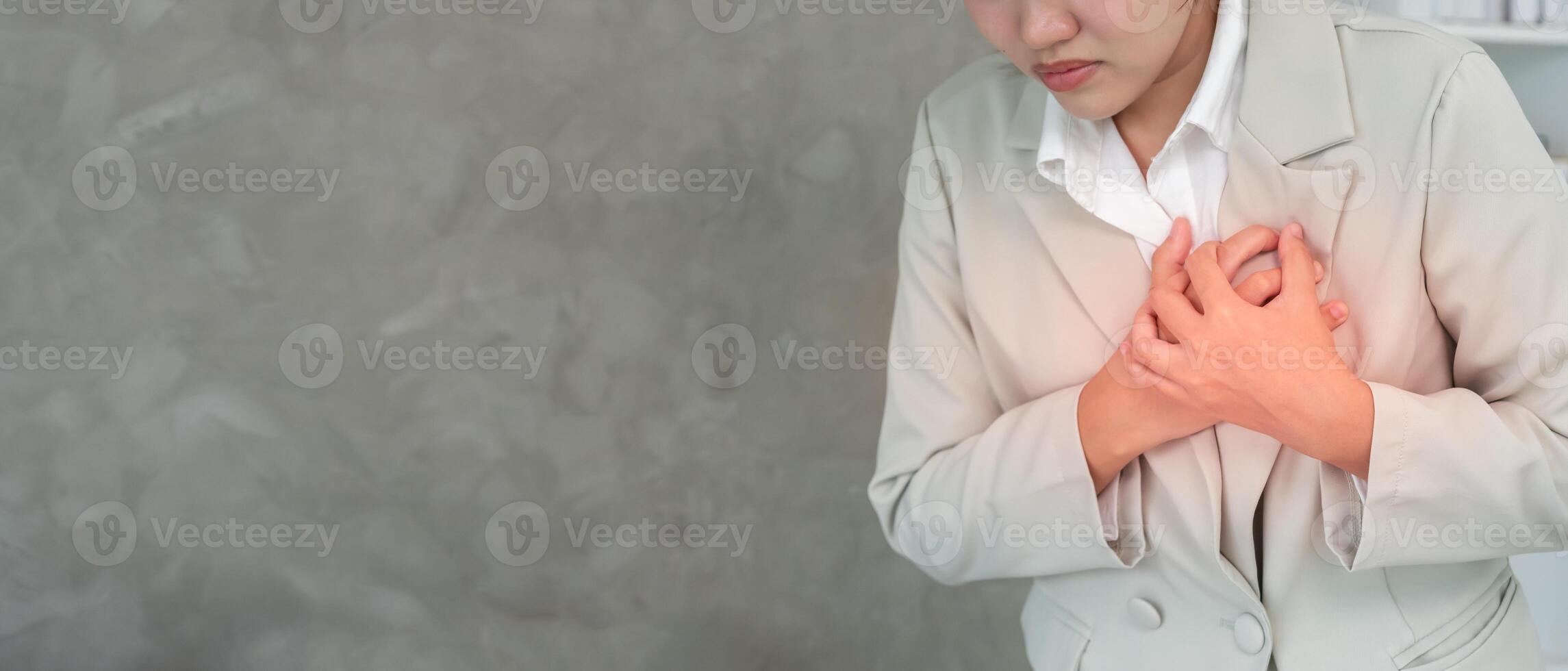 heart attack symptoms. asian woman working hard have chest pain caused by heart disease, leak, dilatation, enlarged coronary heart, press on the chest with painful expression photo