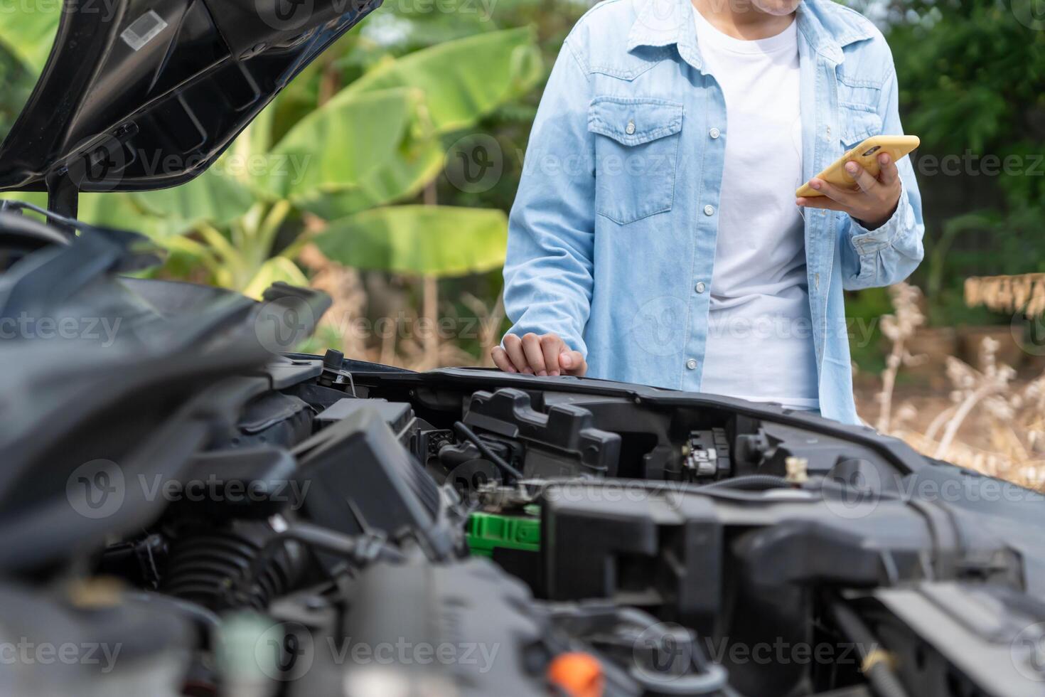 broken car, repair. Woman uses mobile phone check insurance premiums through application due to car accident . Find garage to get car fixed during country tour, waiting for help, emergency. photo