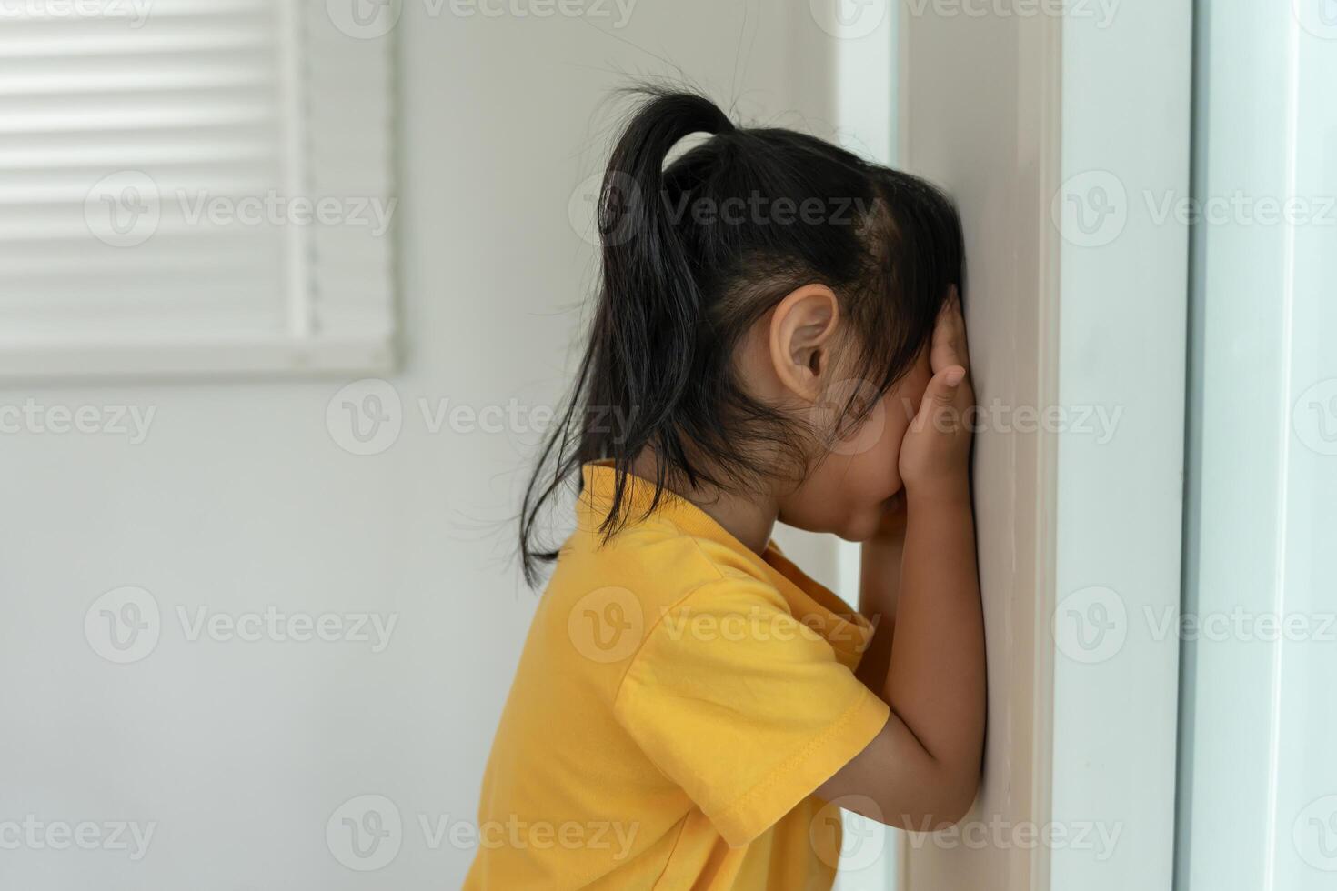 children kid girl cover his eyes with hands, playing hide and seek standing next a wall house, Adorable child having fun in the home. happy family have fun with kids, activity, learning photo