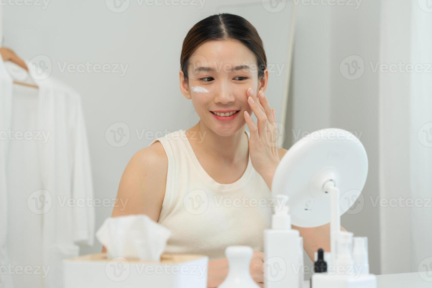 Asia woman sit in front of a mirror. face of a healthy woman applying cream and makeup. Advertisement for skin cream, anti-wrinkle, baby face, whitening, moisturizer, tighten pores serum photo