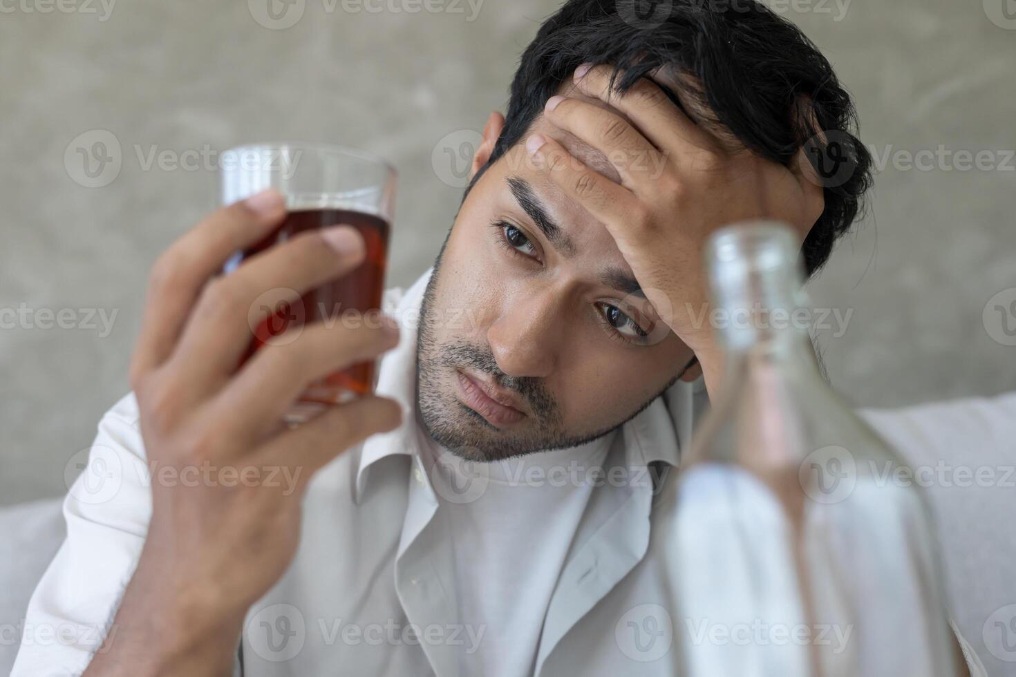 Depressed young man addict feeling bad drinking whiskey alone at home, stressed frustrated lonely drinking alcohol suffers from problematic liquor, alcoholism, life and family problems photo