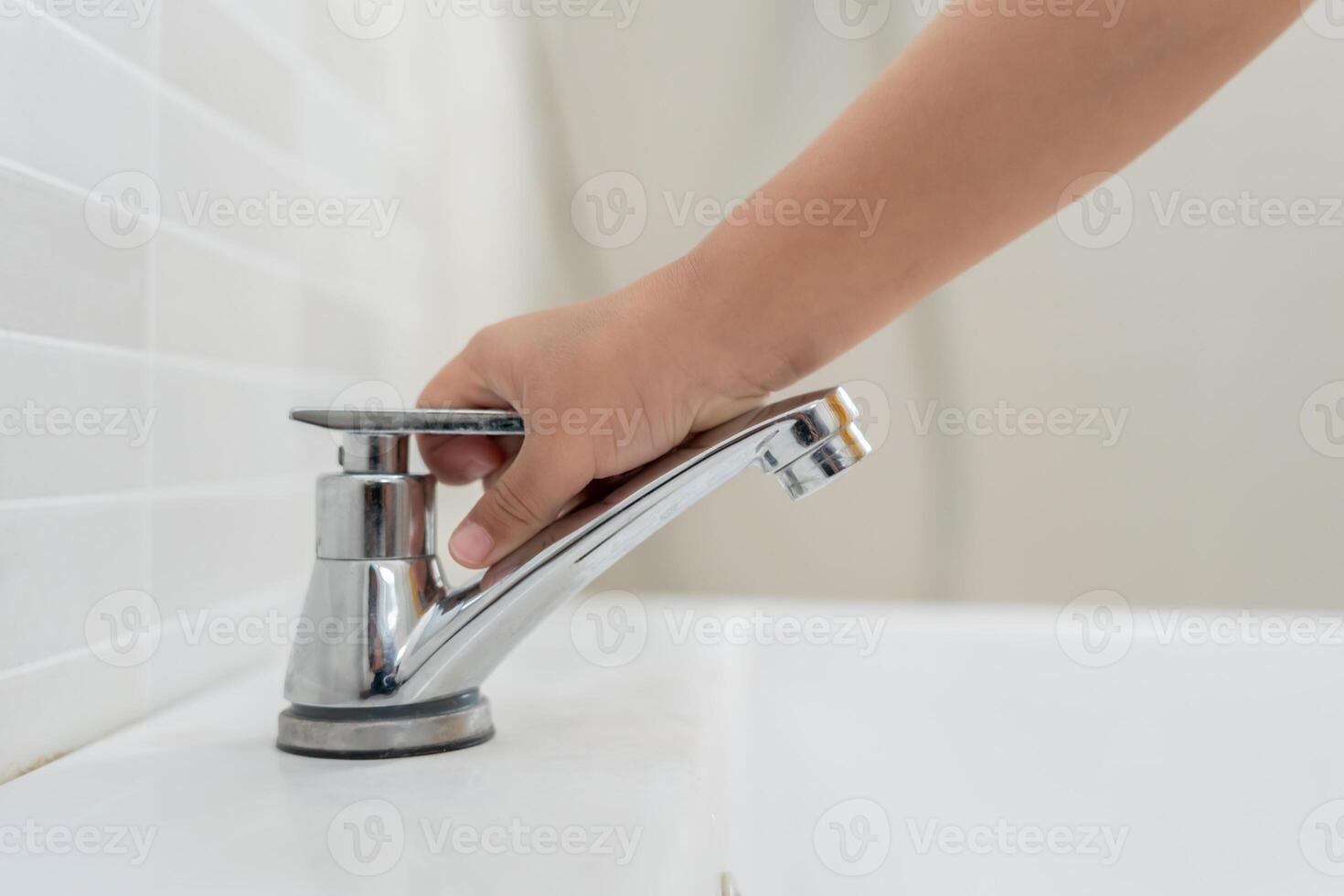 Save water Little kid keeps turning off the running water in the bathroom to protect environment. Greening planet, reduce global warming, Save world, life, future, risk energy, crisis , water day. photo