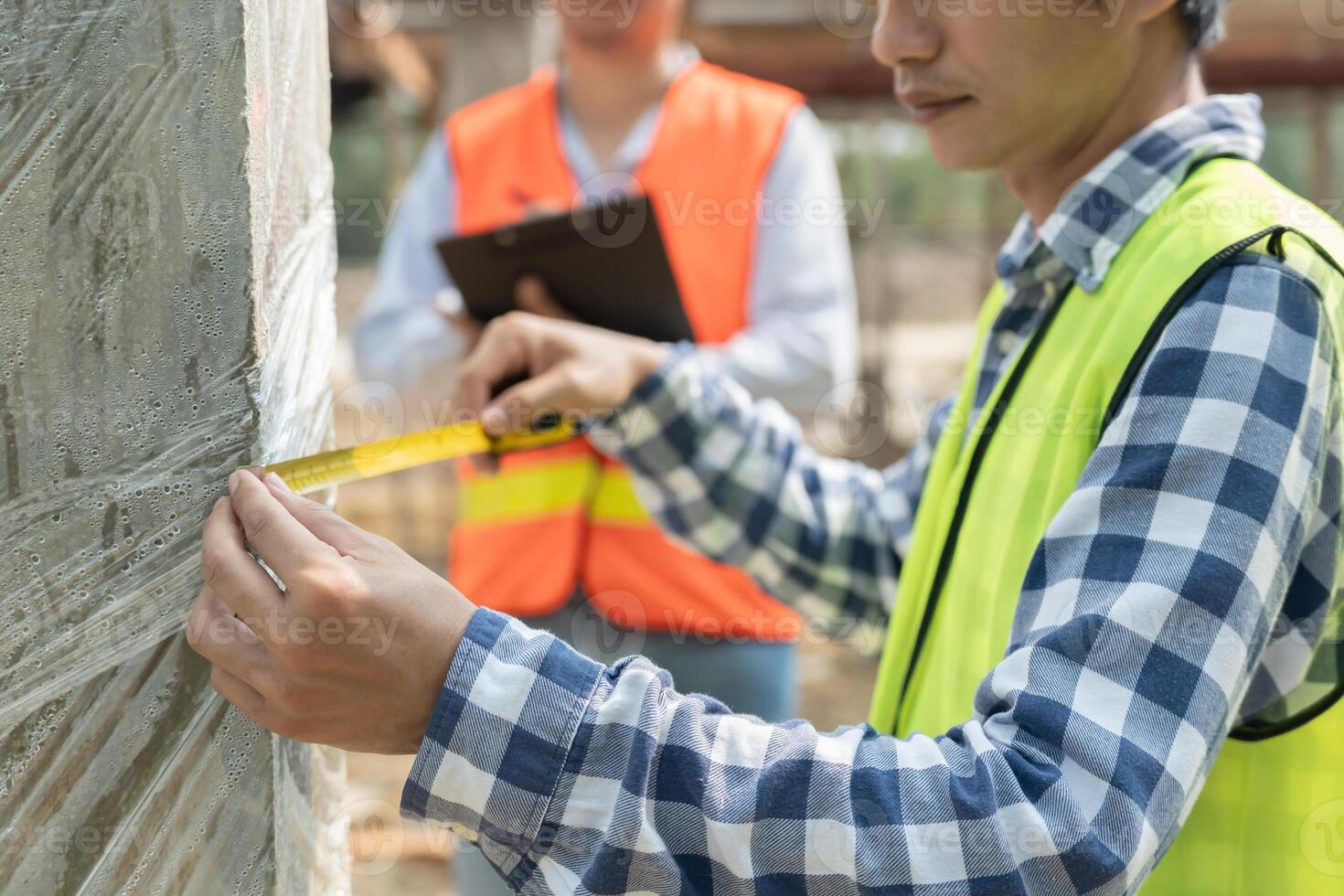inspector or engineers is inspecting construction and quality assurance check dimension of house by using a tape measurement. Engineers or architects or contactor work to build the house before sell. photo