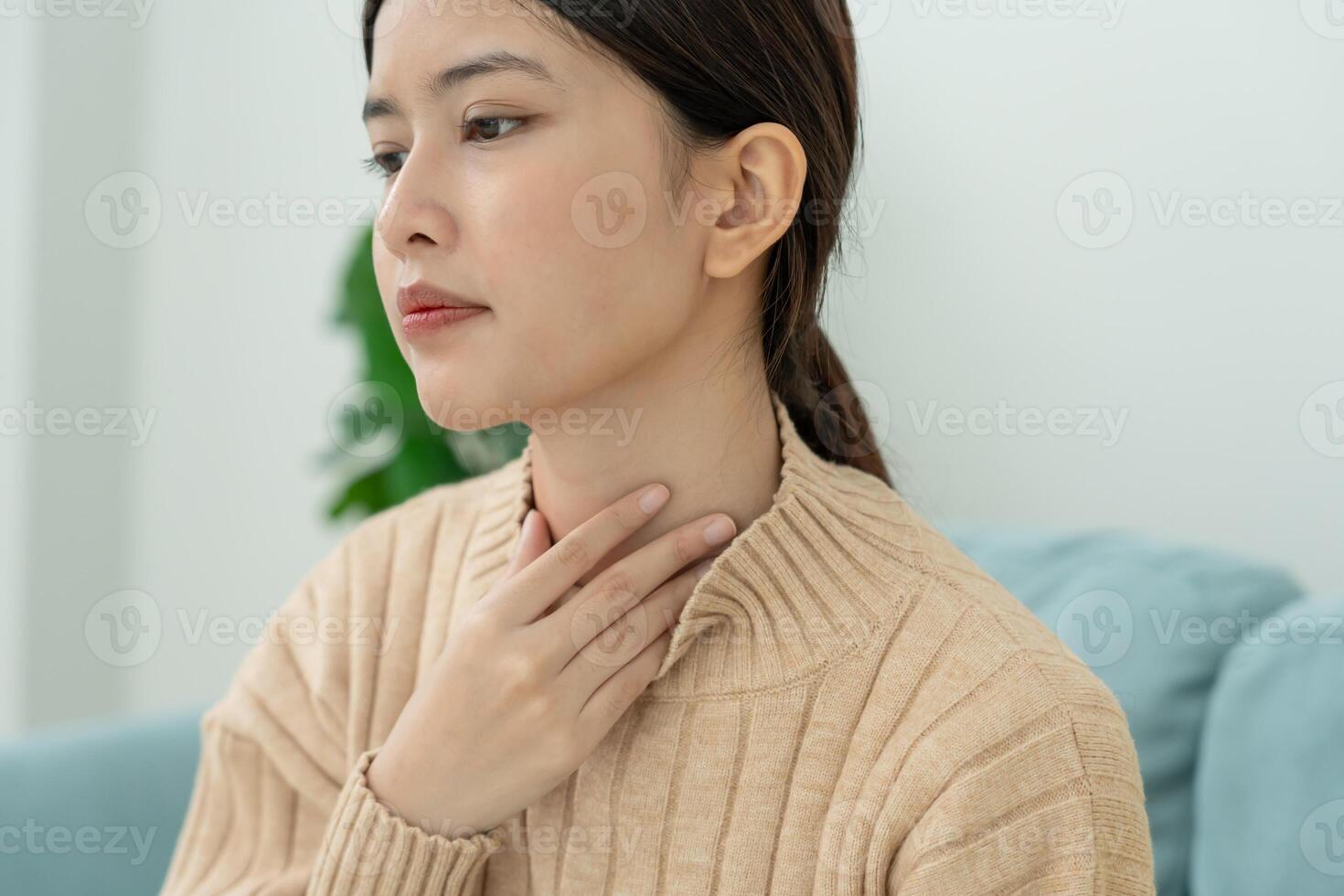 Asian woman put on neck due to a sore throat. female tonsillitis causes a inflammation. treated by taking water, taking antibiotics, consult a doctor, virus, corona virus. photo