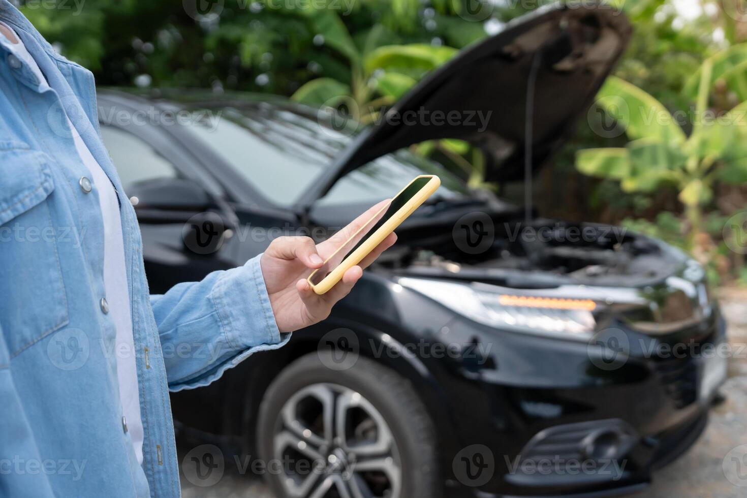 breakdown broken car repair. Woman uses mobile phone check insurance premiums through application due to car accident . Find garage to get car fixed during country tour, waiting for help, emergency. photo
