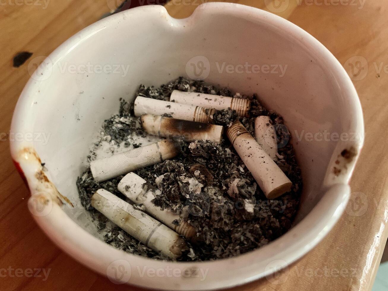 Cigarette ashtray full of cigarette ash on the table photo