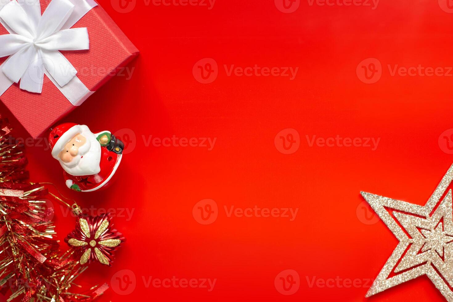 Red gift box, tinsel, figurine of Santa Claus with Christmas decorations in the form of gold stars, on a red background photo
