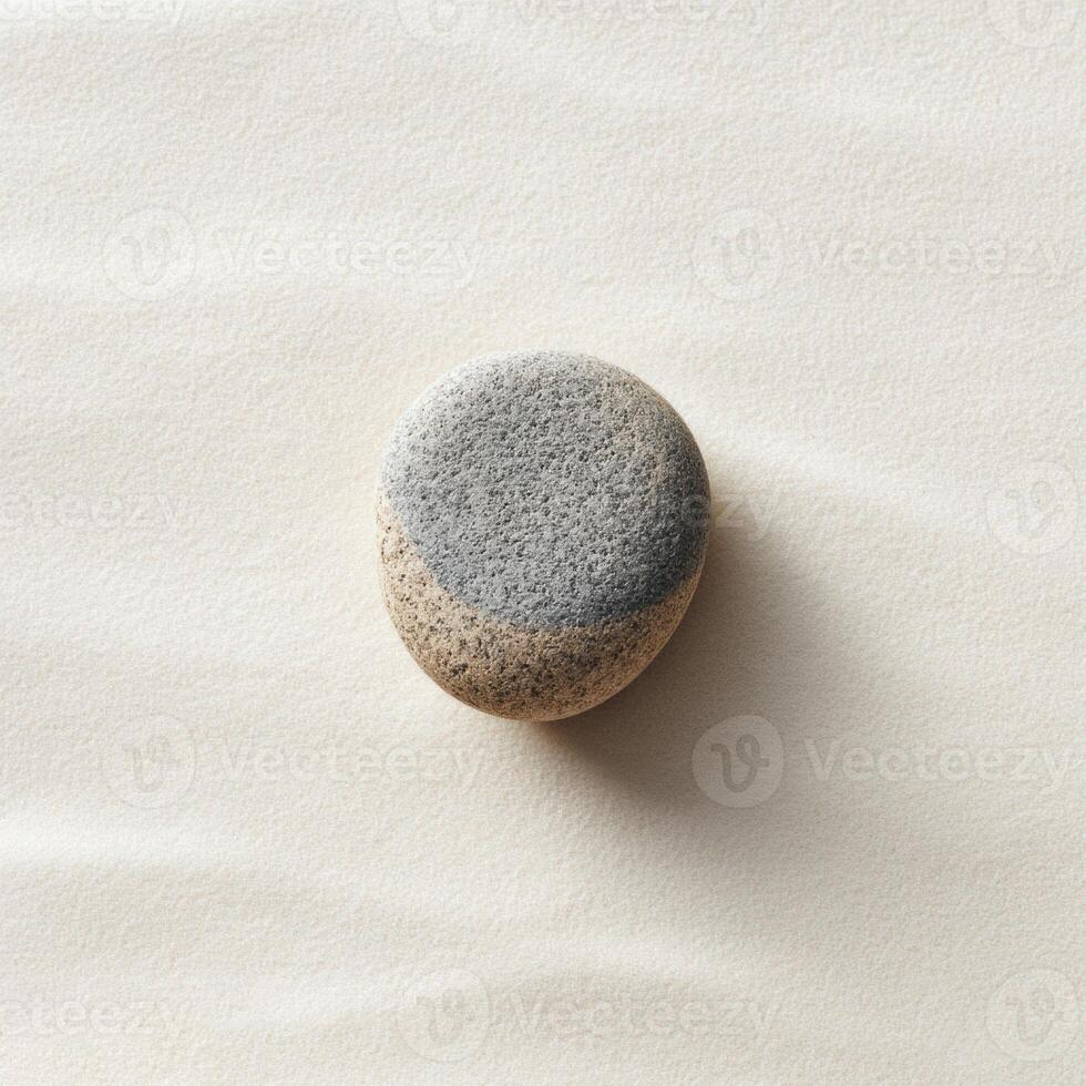 A stone on a white surface with a gray spot photo