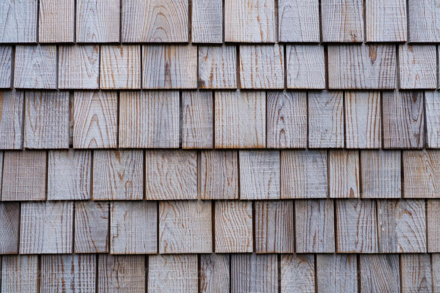 Textured wooden shingles covering a rustic building exterior during daylight hours photo