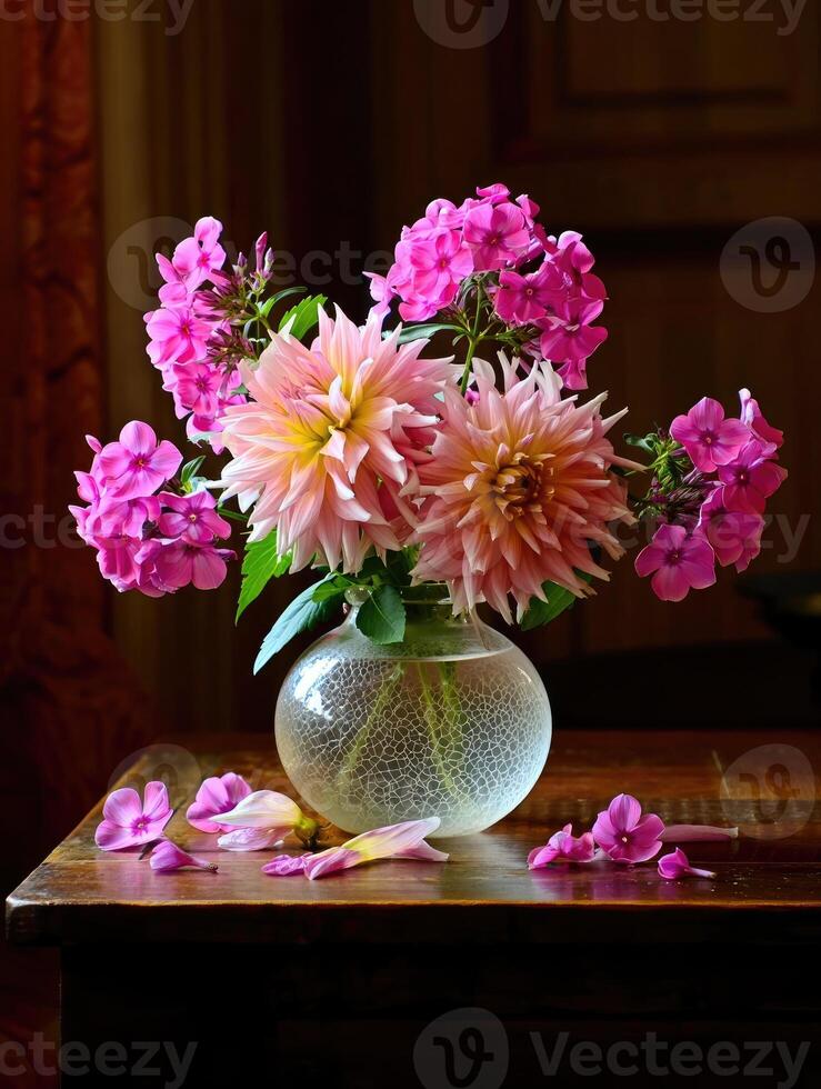 Colorful floral arrangement in a clear vase on wooden table with petals scattered photo