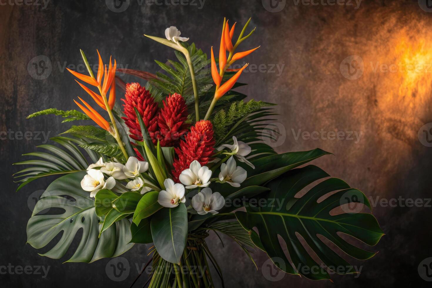 A beautiful, artful arrangement of tropical flowers and green foliage set in a studio. photo