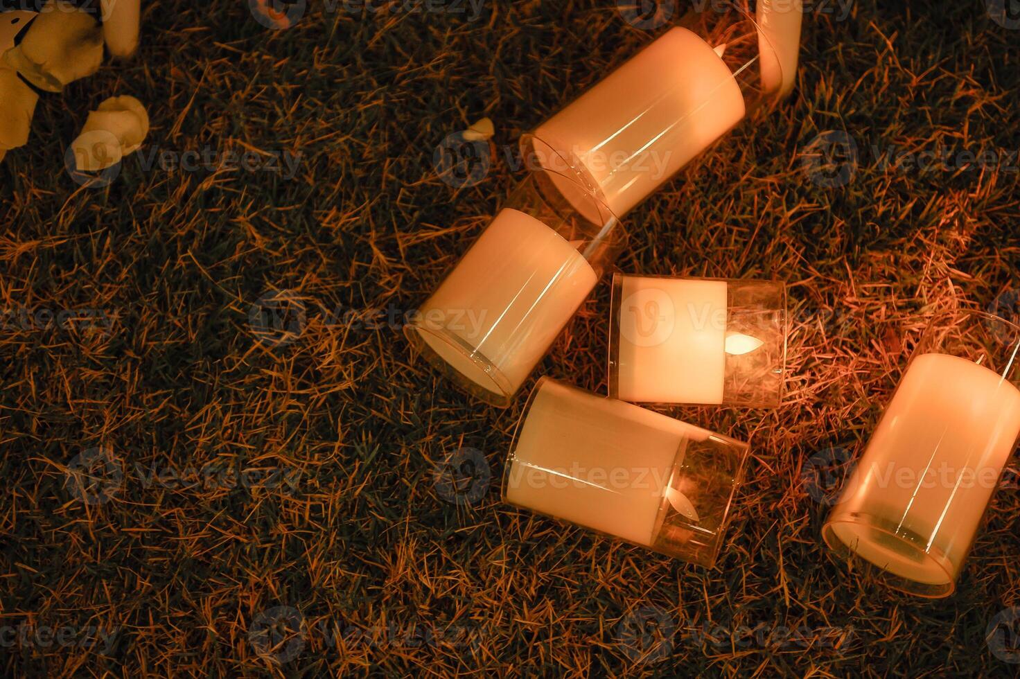 Candles glowing and scattered on grass at night photo