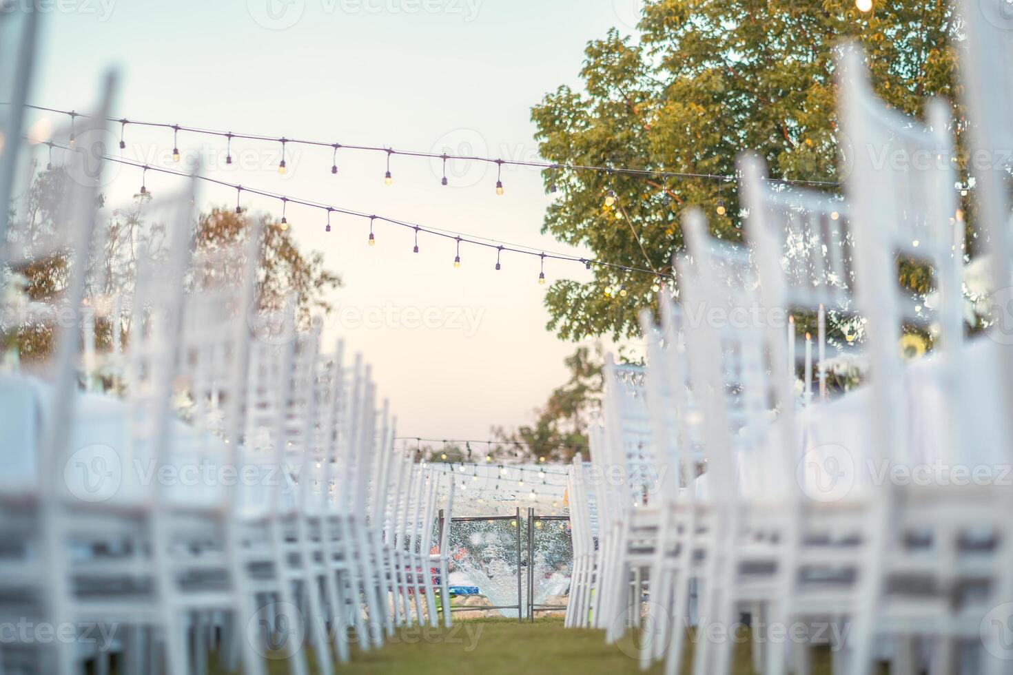Elegant wedding long table with candle, white rose flower and white chairs in the garden photo