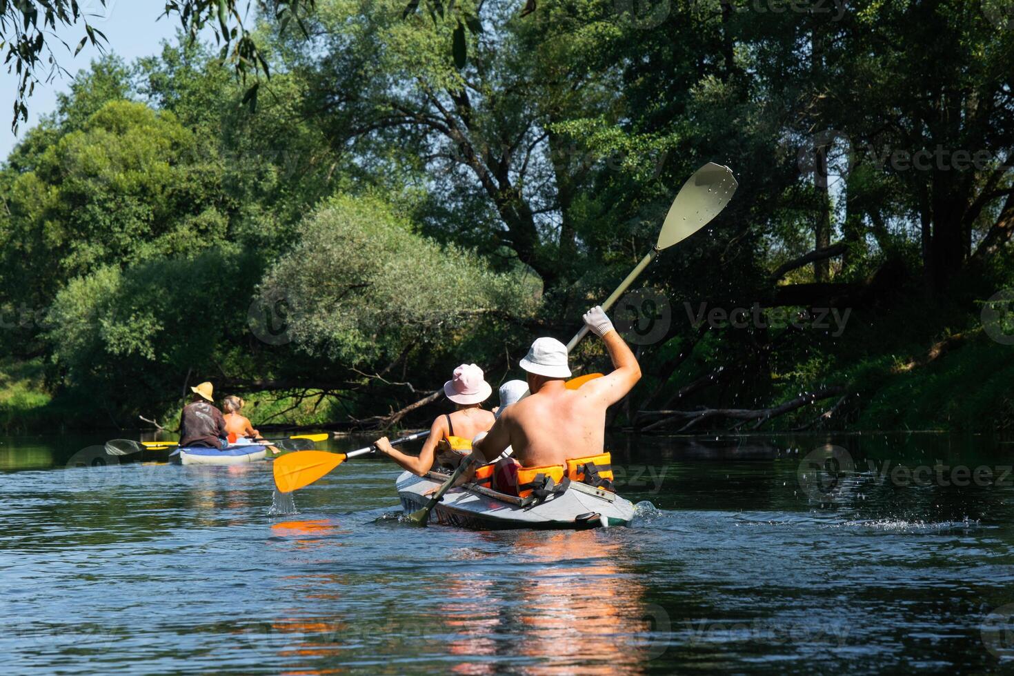 A group of people paddling a canoe down a river photo