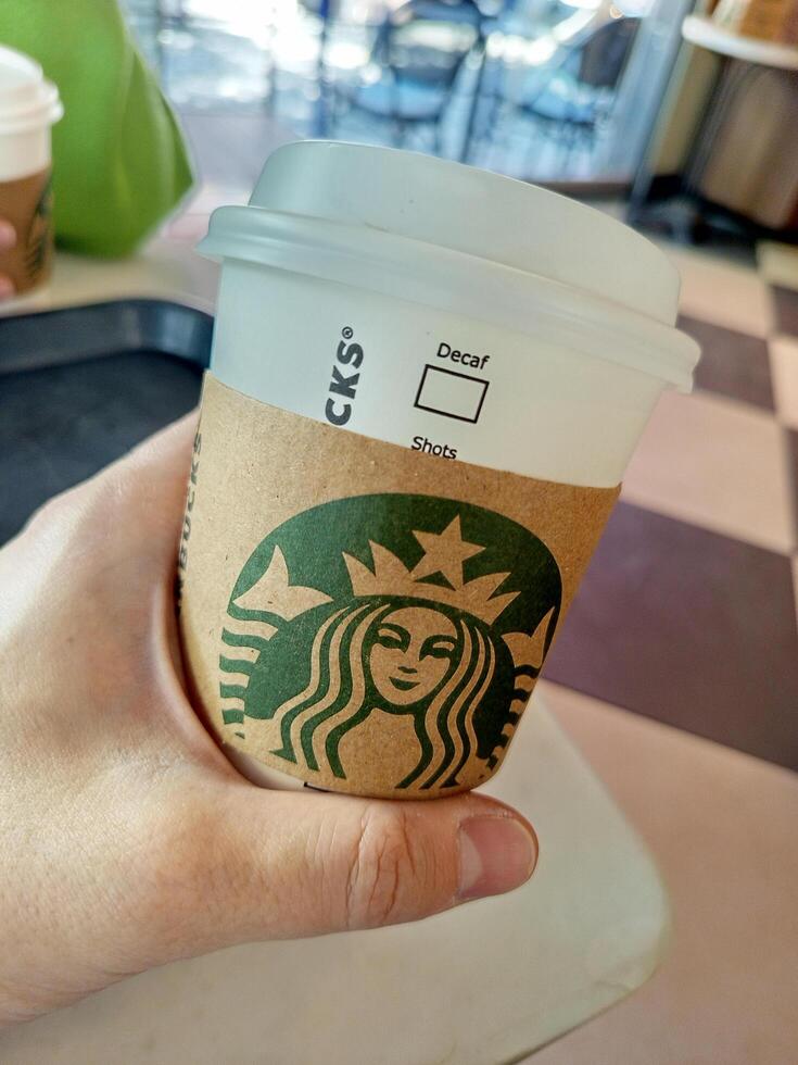 Turkey, Istanbul May 11, 2025 hand holding a cup at Starbucks in a coffee shop... photo