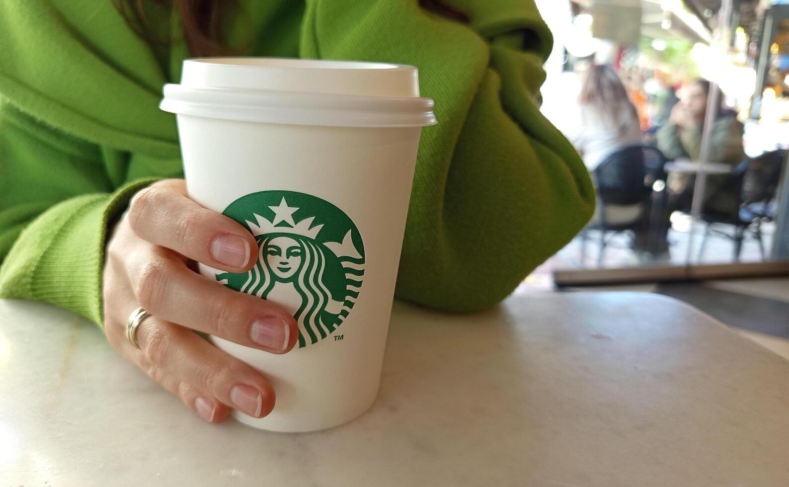 Turkey, Istanbul May 11, 2025 hand holding a cup at Starbucks in a coffee shop. photo