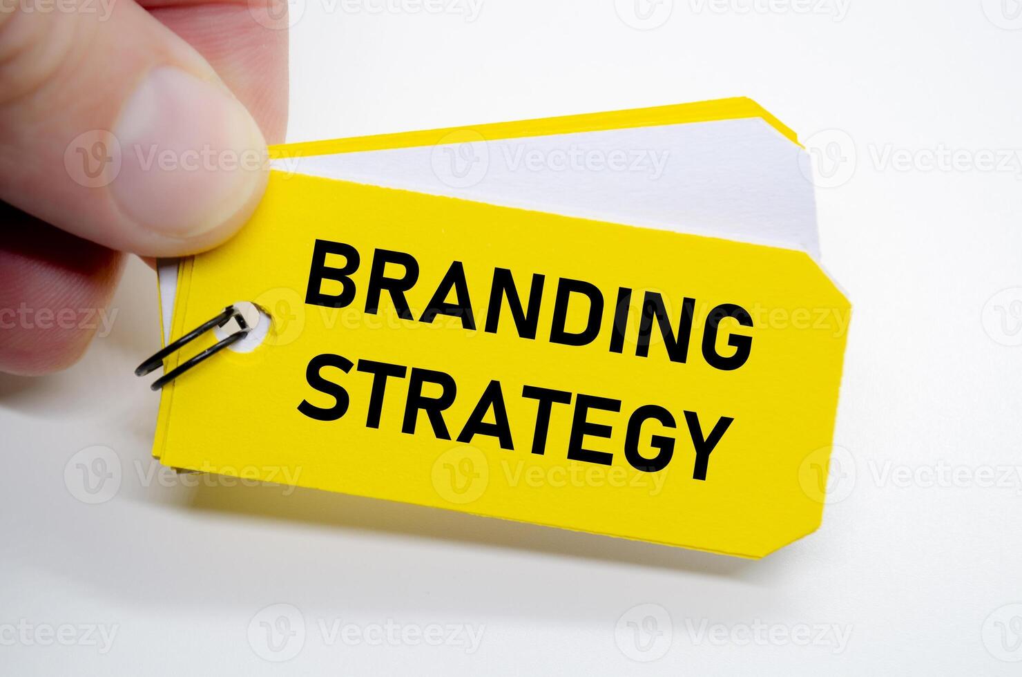 Branding strategy in bold black font on yellow sticky note with hand holding the concept. photo
