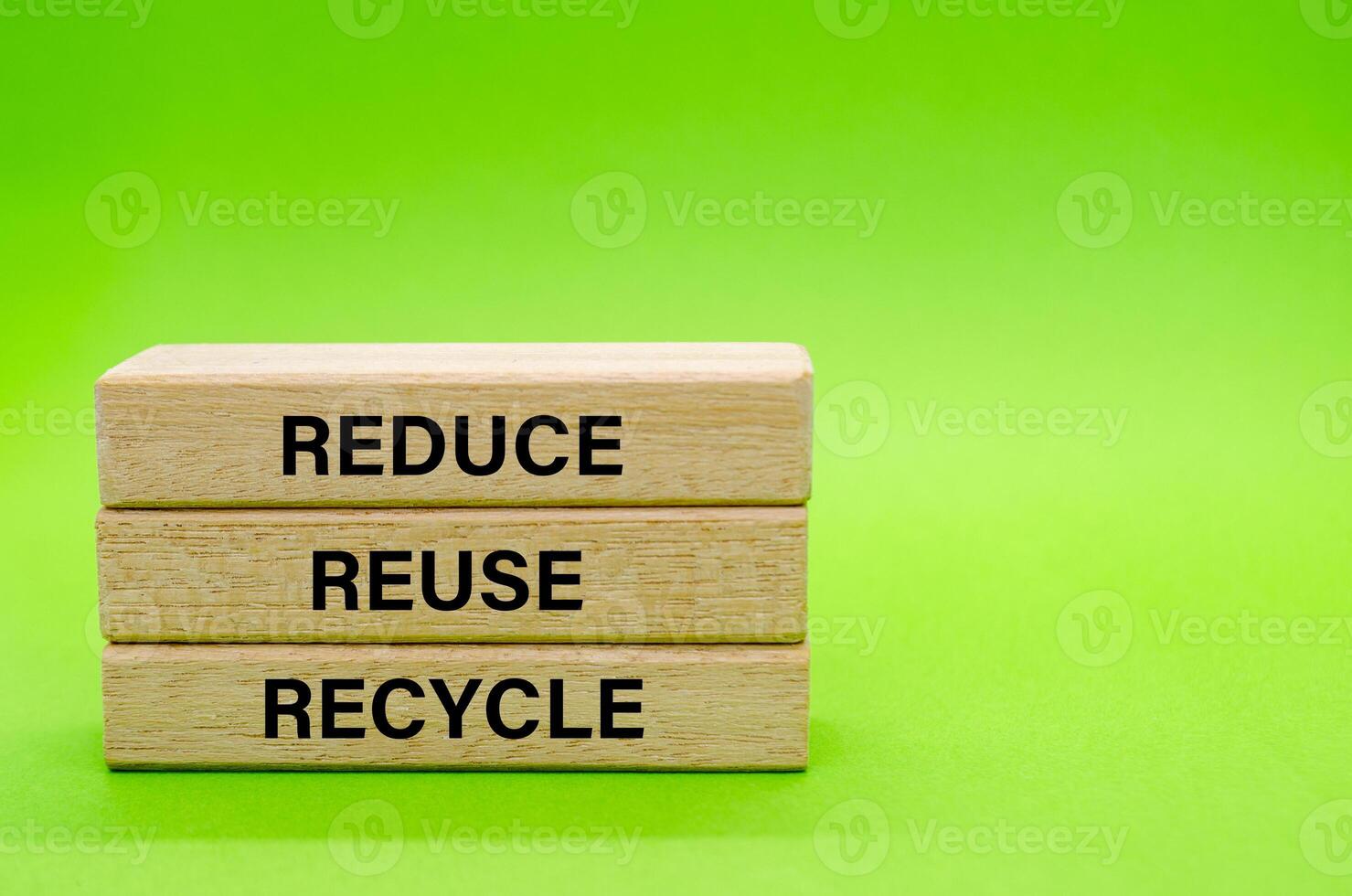Wooden blocks with Reduce, Reuse and Recycle text placed on green surface. Symbolizing commitment to eco friendly habits and waste reduction. photo