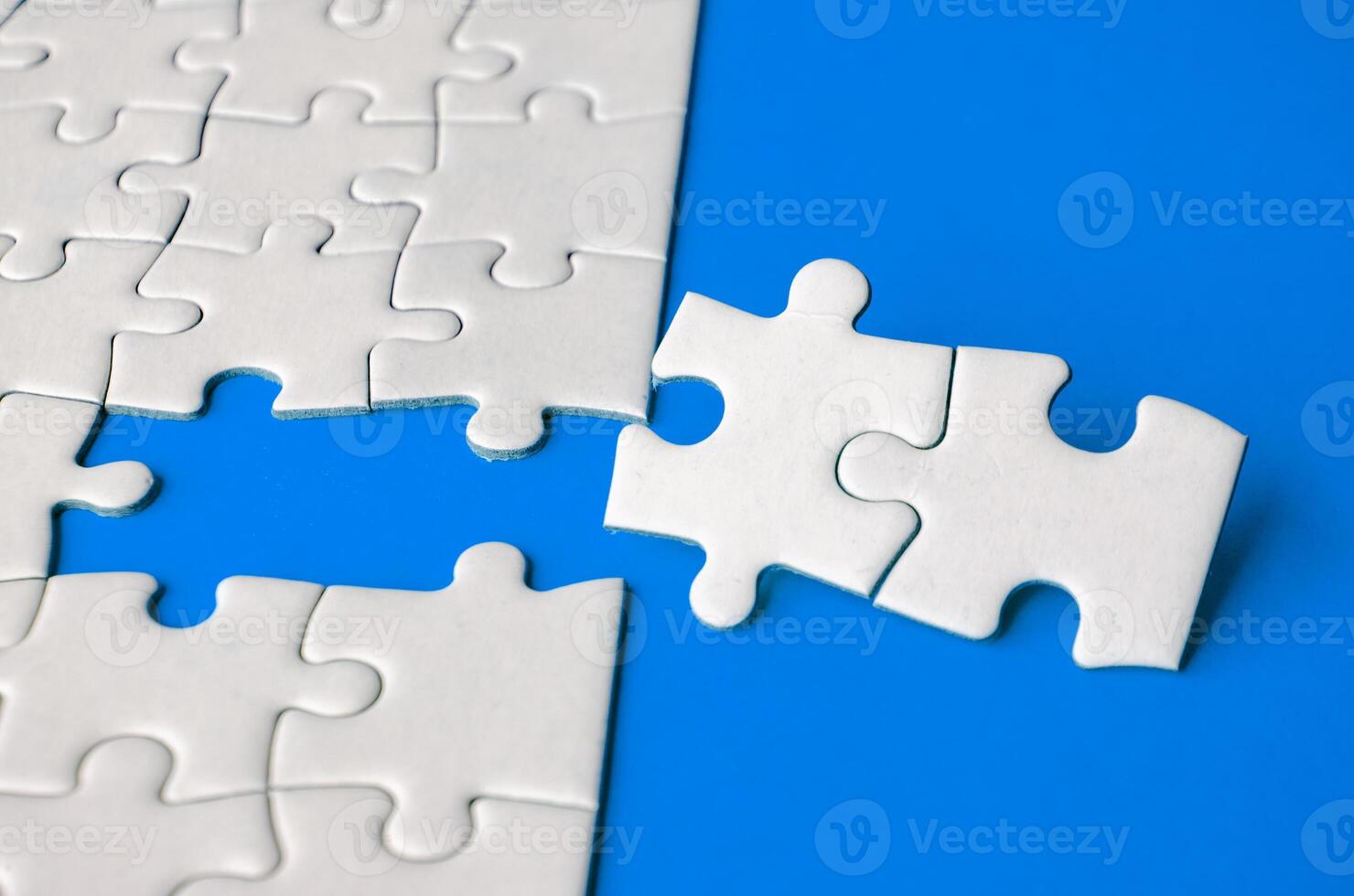 Close up view of missing white jigsaw puzzles, symbol of partnership and unity on blue background photo