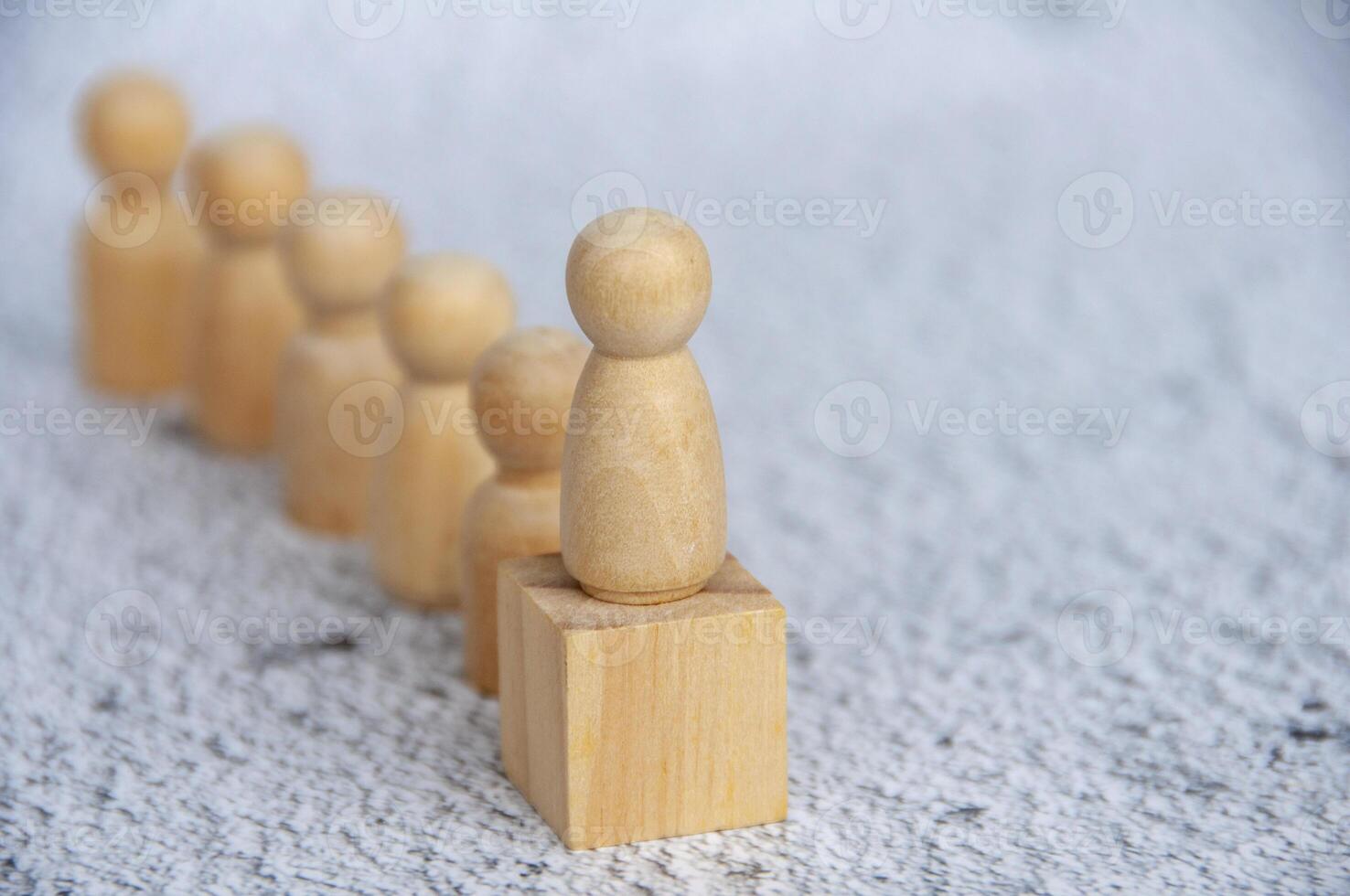 Wooden doll on to of wooden cube with wooden dolls followers background photo