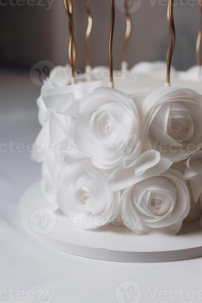 A stunning white cake, elegantly decorated with sugar roses and golden candlesperfect for weddings or anniversaries, enhancing every celebration and creating unforgettable memories photo