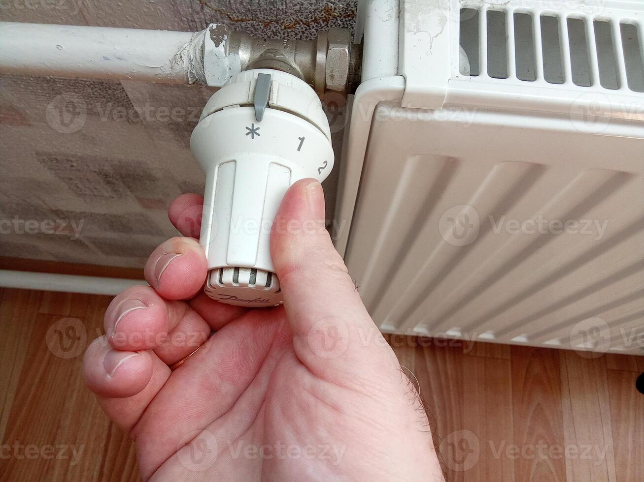 A man's hand turns the battery-powered radiator. photo