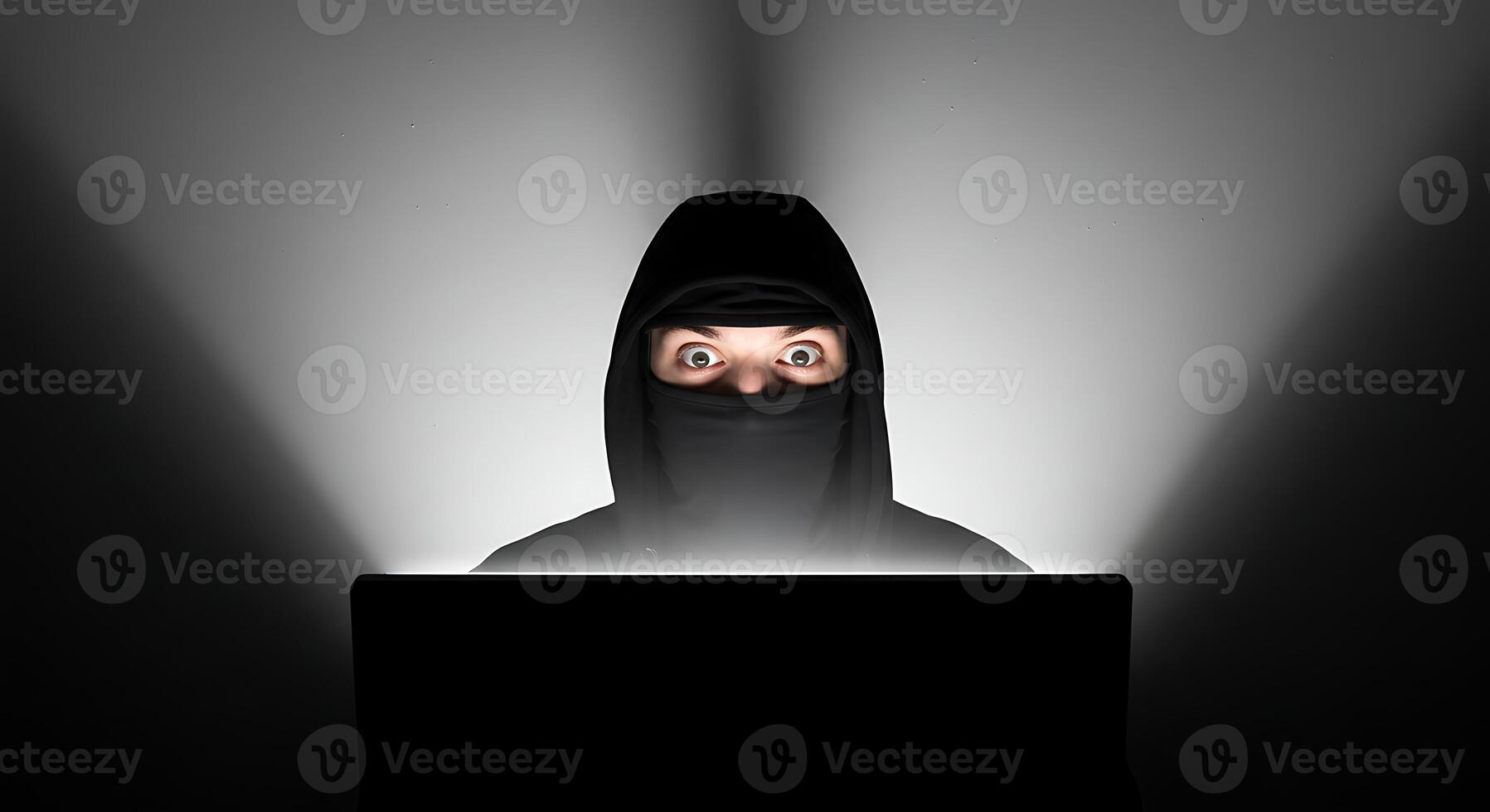 Person in Hood Using Computer at Night with Focused Expression photo