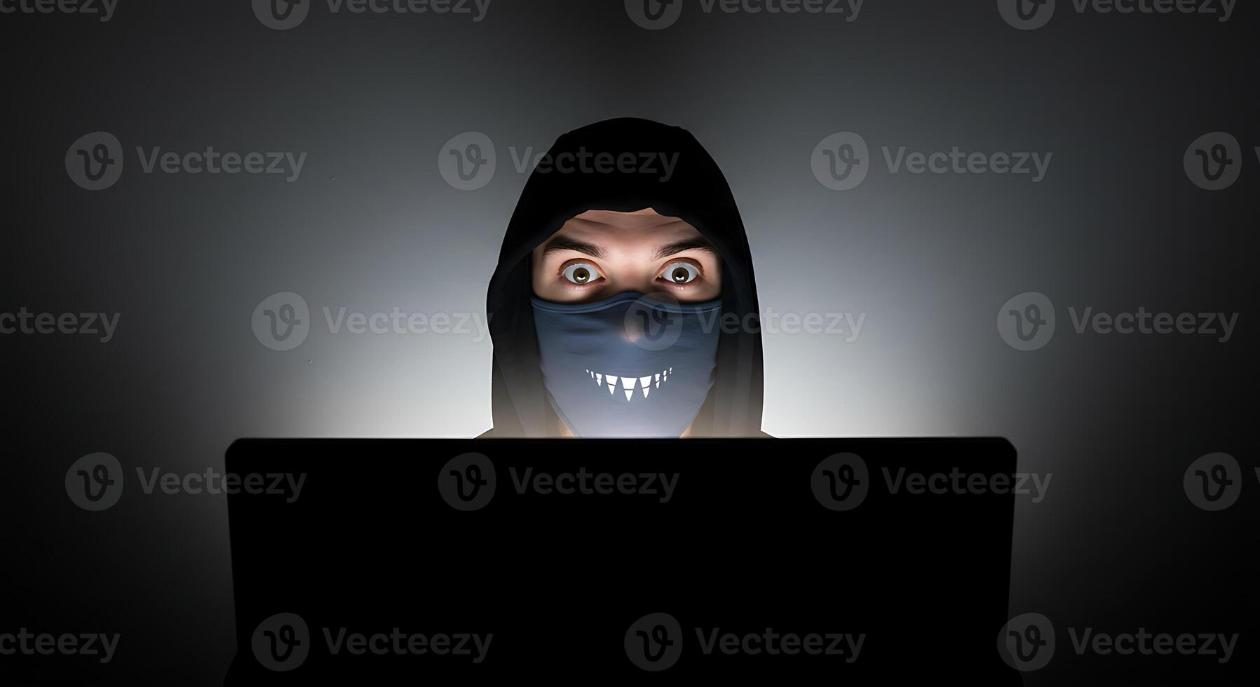 Person Using Laptop Wearing Mask and Hood in Dark Room photo
