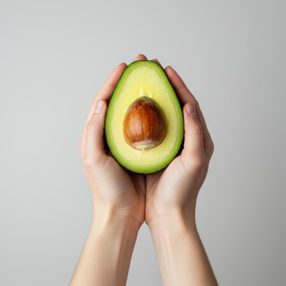Hands gently cradling a vibrant avocado half, displaying the pit's rich texture photo