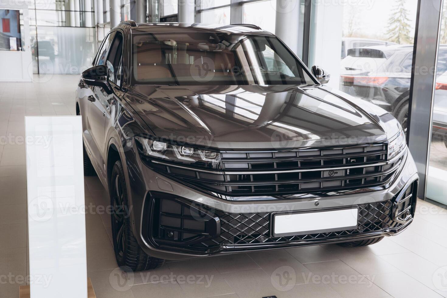New gray suv car parked in modern showroom reflecting light on polished hood photo
