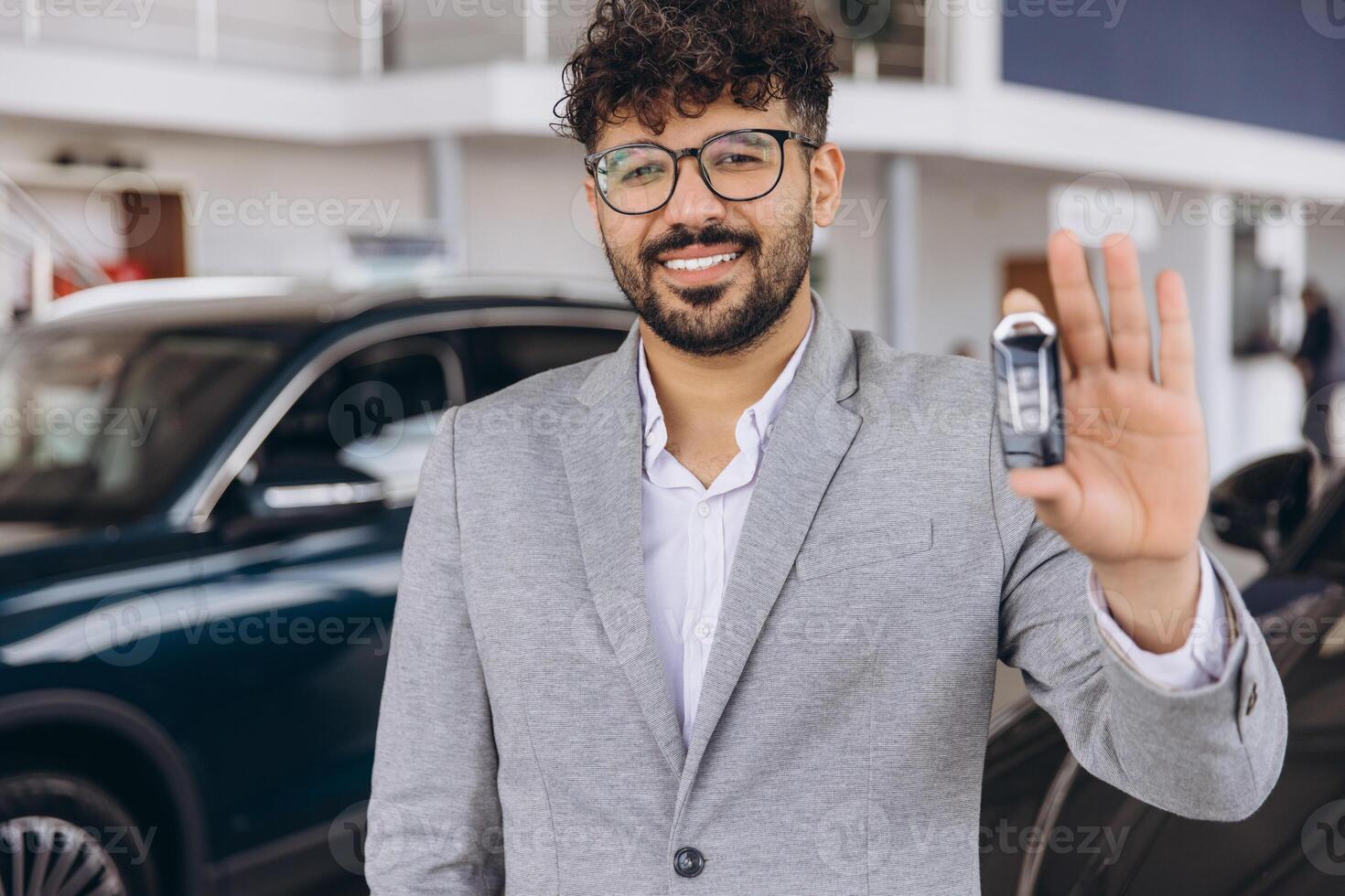 Smiling Car Salesman Showing New Car Key in Dealership photo