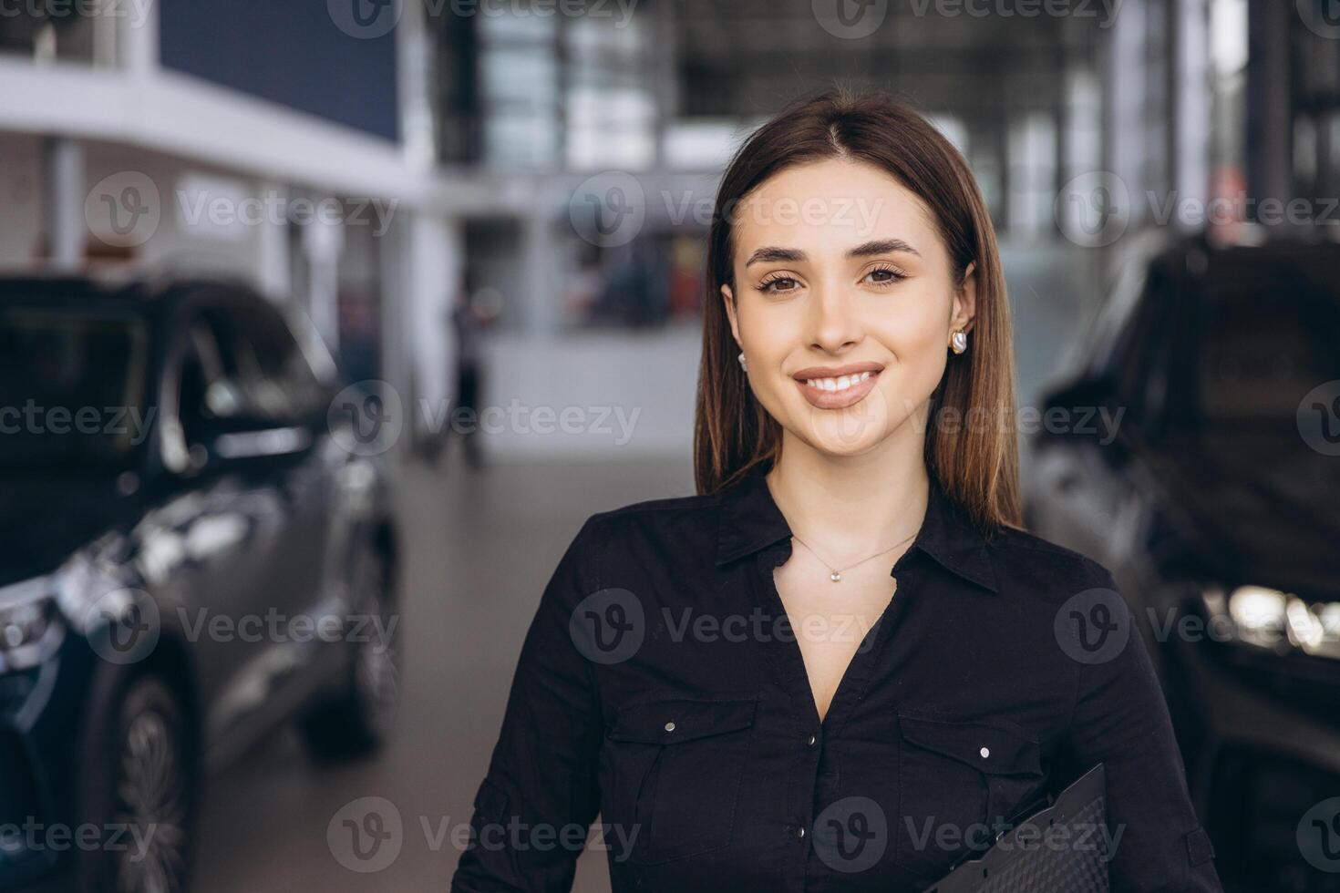 Saleswoman smiling in a car dealership showroom photo